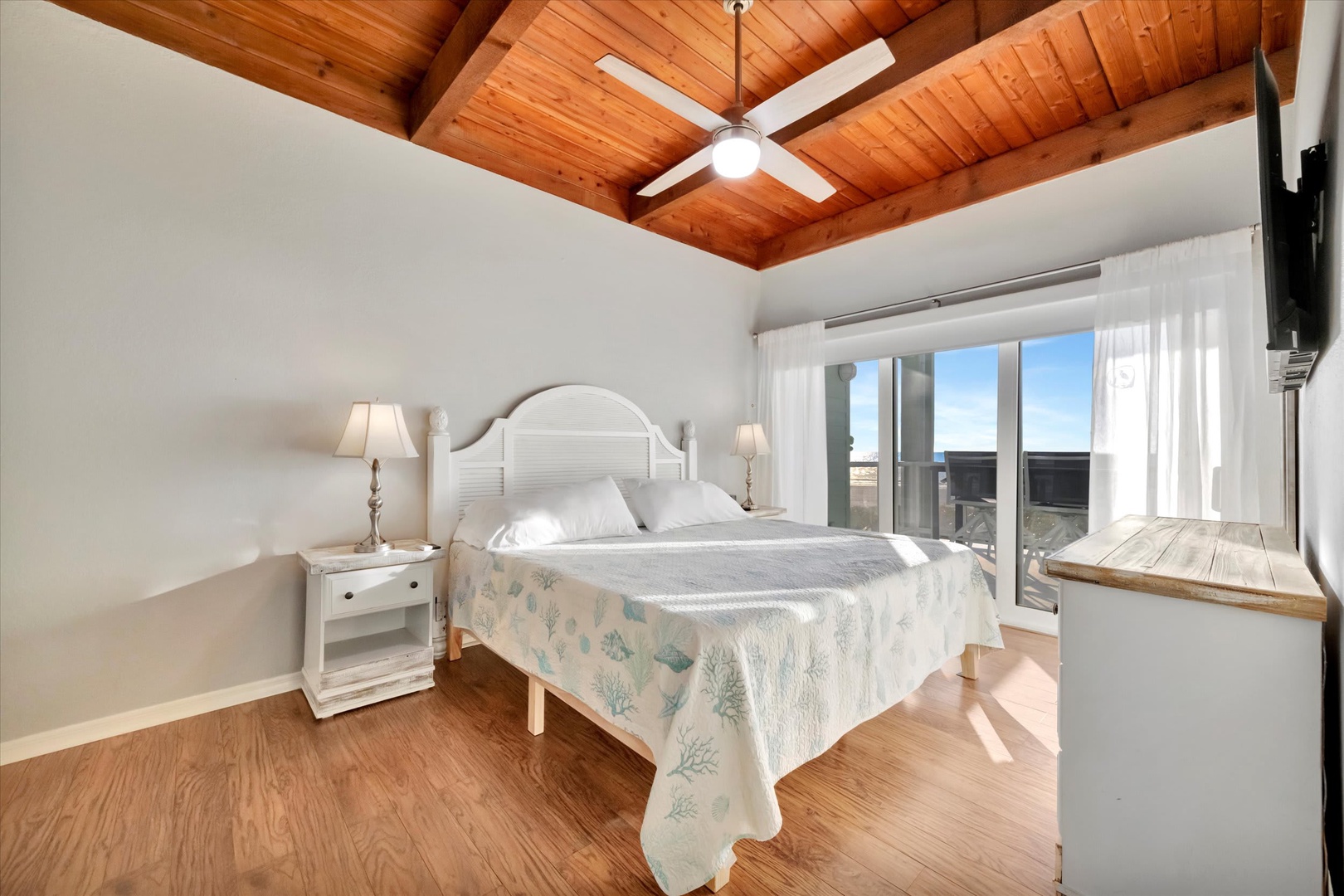 Wake up to sunlight streaming through your windows and the warmth of natural wood overhead. This serene bedroom invites you to unwind beneath vaulted ceilings, with coastal-inspired touches and plenty of space to truly relax.