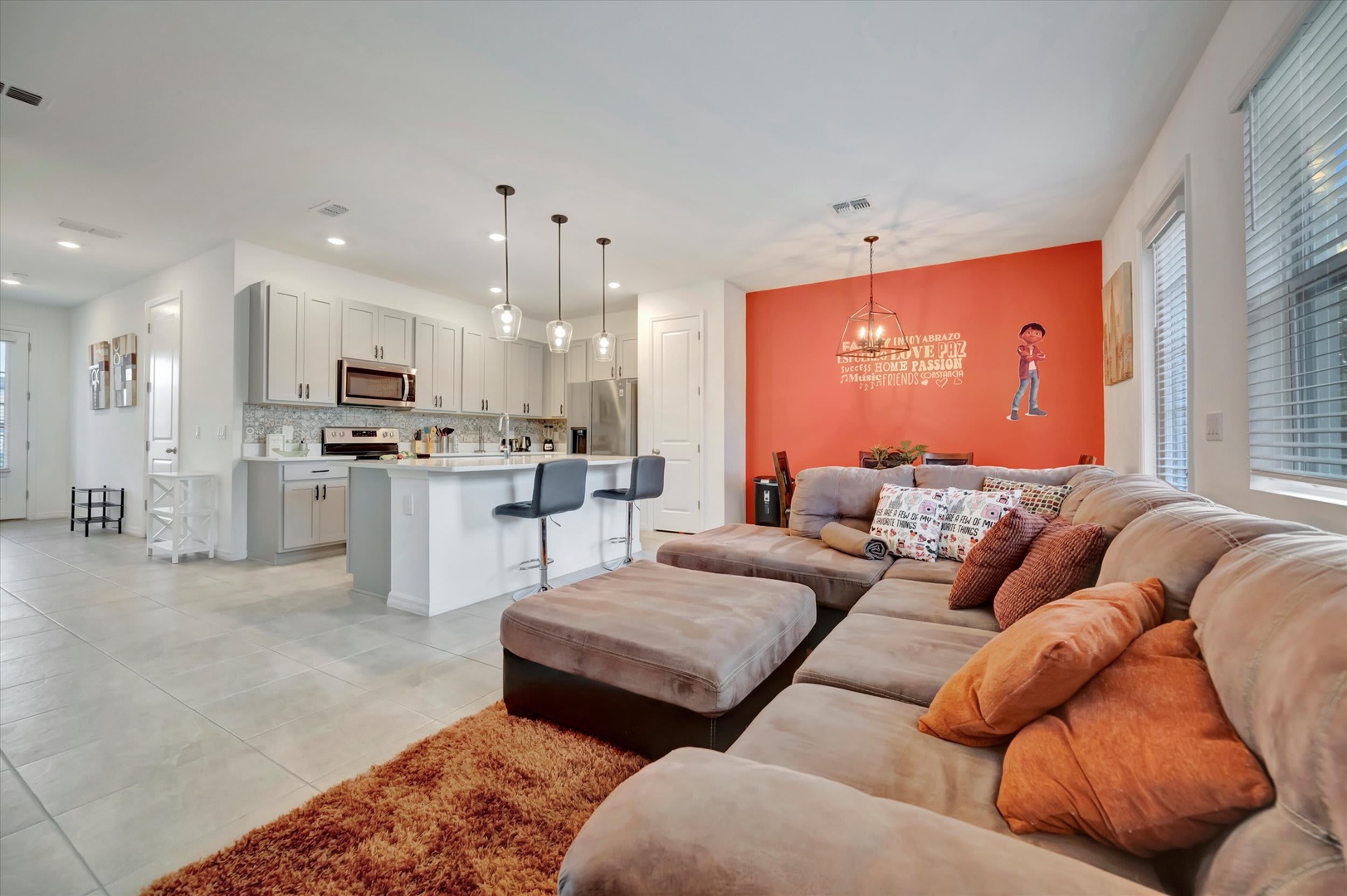 Sink into the plush sectional after a day of exploring, or gather around the bright open kitchen for cooking and conversation. Modern lighting and a vibrant accent wall create a welcoming vibe perfect for your getaway.