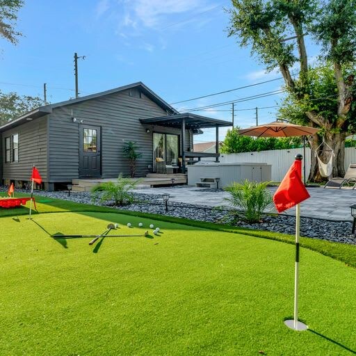 The property features a private putting green set in a beautifully landscaped backyard with modern outdoor seating and covered entertainment area.
