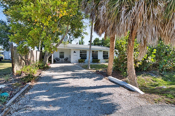 Tropical palms and lush greenery line the driveway, welcoming you to your private coastal retreat where relaxation begins the moment you arrive.