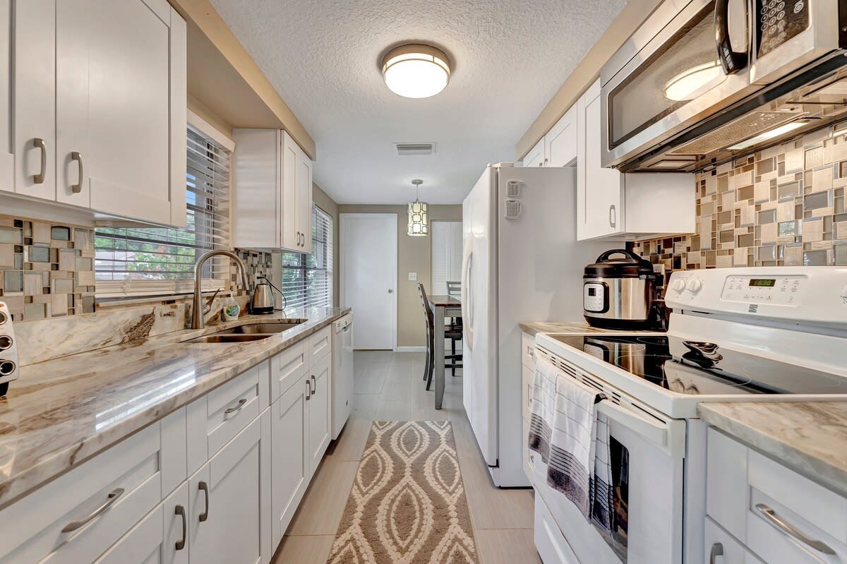 Cook your favorite meals in this bright, fully equipped kitchen with modern appliances and stylish tile backsplash. The gleaming counters and crisp white cabinetry give you plenty of space to prepare everything you need.