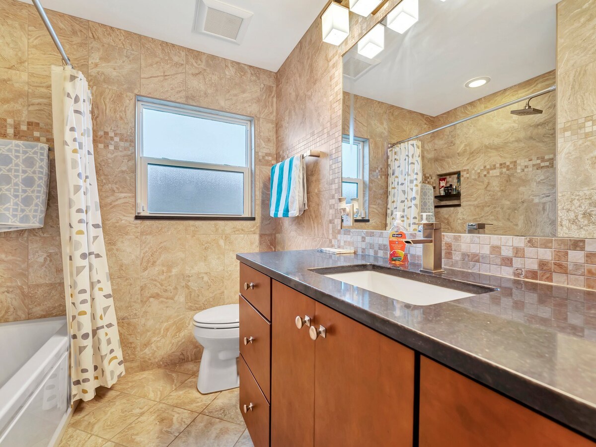 Step into your beautifully tiled bathroom with warm amber tones and modern touches. The sleek vanity, fresh towels, and skylight-lit shower create a spa-like retreat for your morning routine.