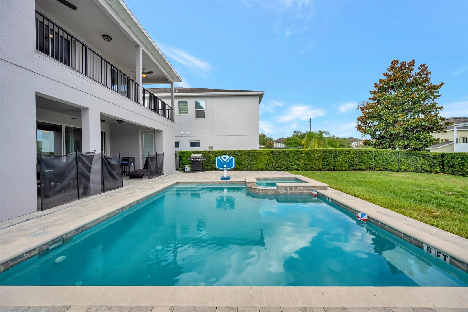 This spacious two-story vacation rental features a pristine private pool with an attached spa, surrounded by travertine pavers and a well-manicured lawn—perfect for sunny Florida afternoons and poolside relaxation.