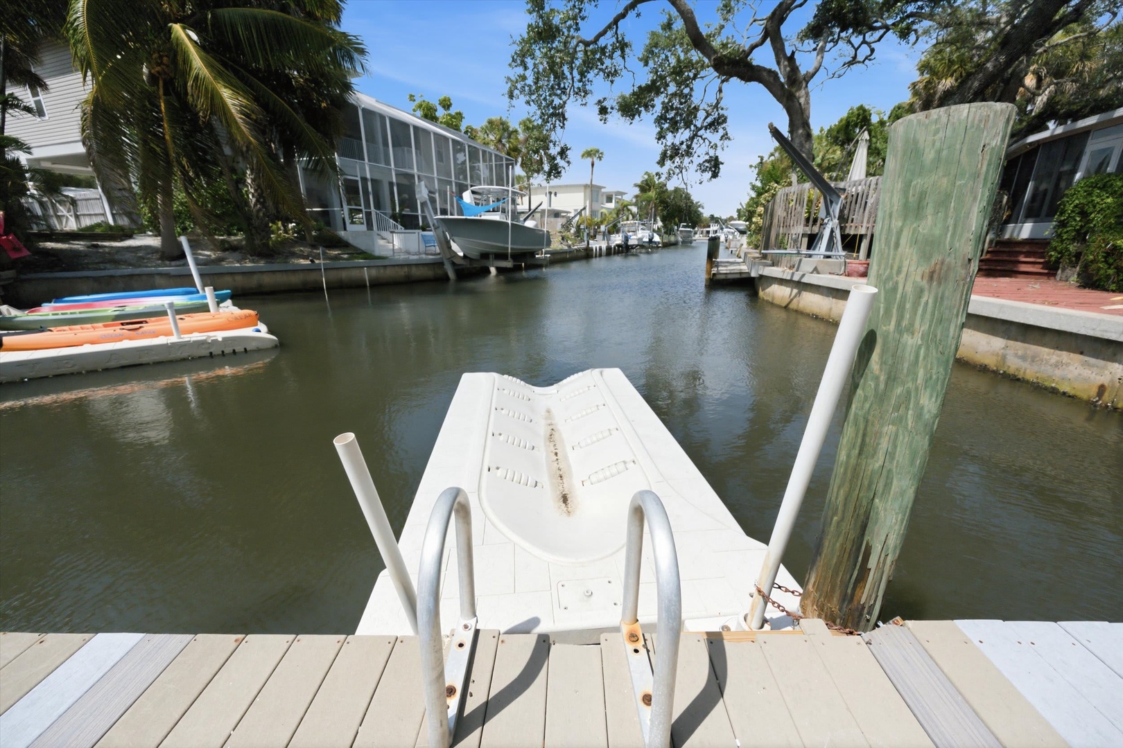 Waterfront property situated along a tranquil canal with private dock access, boats, and lush tropical landscaping. The neighborhood features canal-side homes and easy water access.