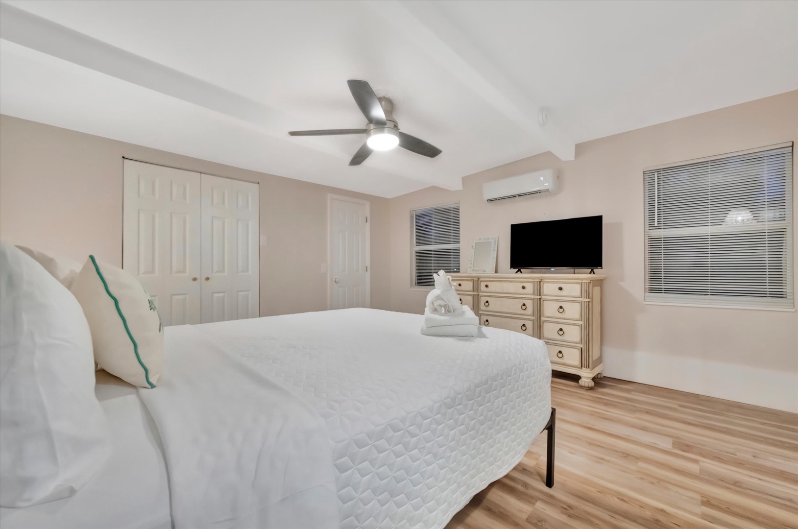 Drift off in your spacious, light-filled bedroom with plush bedding, modern AC, and warm wood floors creating a peaceful retreat for restful nights.