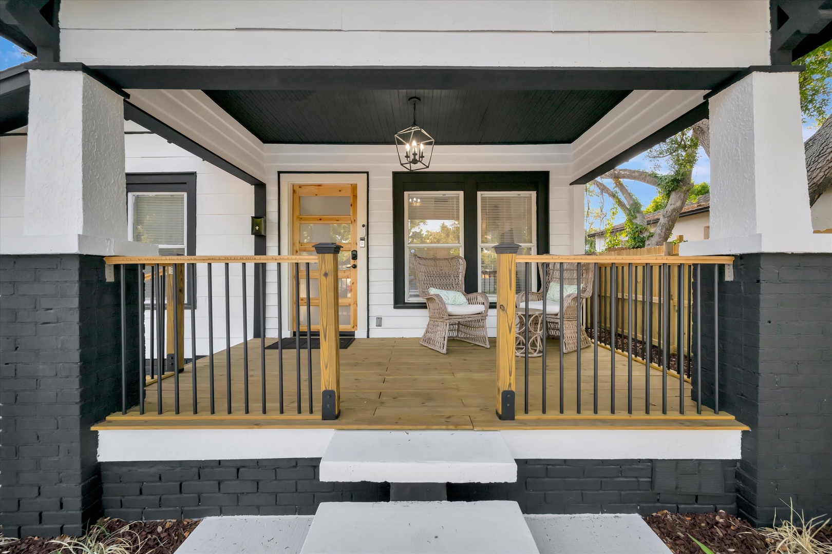 The charming front porch welcomes you with wicker seating and warm wood accents, offering a peaceful spot to enjoy your morning coffee or unwind after a day of exploring.