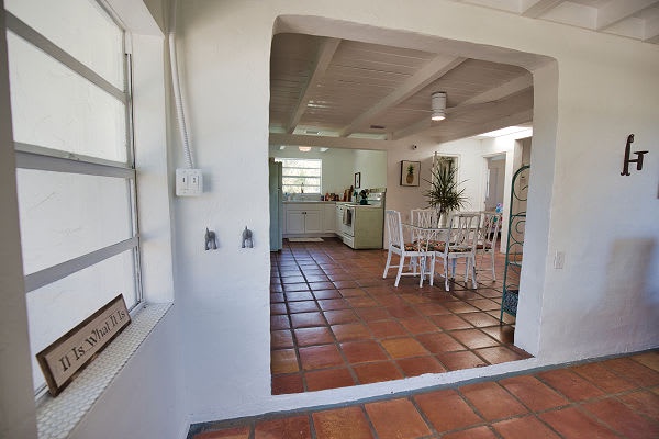 Step through the welcoming archway into your open-concept kitchen and dining space, where warm terracotta tiles and soft coastal light create the perfect backdrop for your vacation meals together.