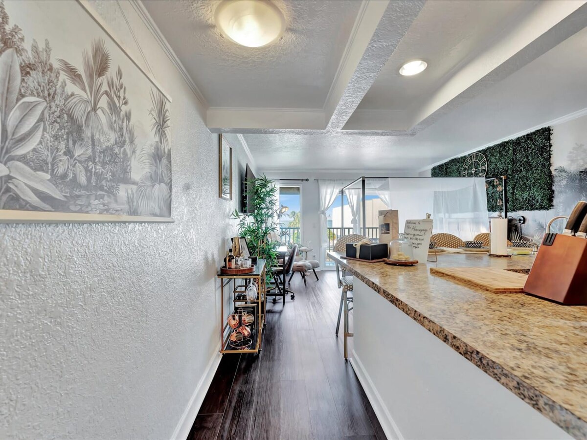 A bright, welcoming entrance hallway with botanical wall art and modern touches leads you into your stylish retreat. Natural light from the open living area ahead creates a warm, inviting atmosphere from the moment you arrive.
