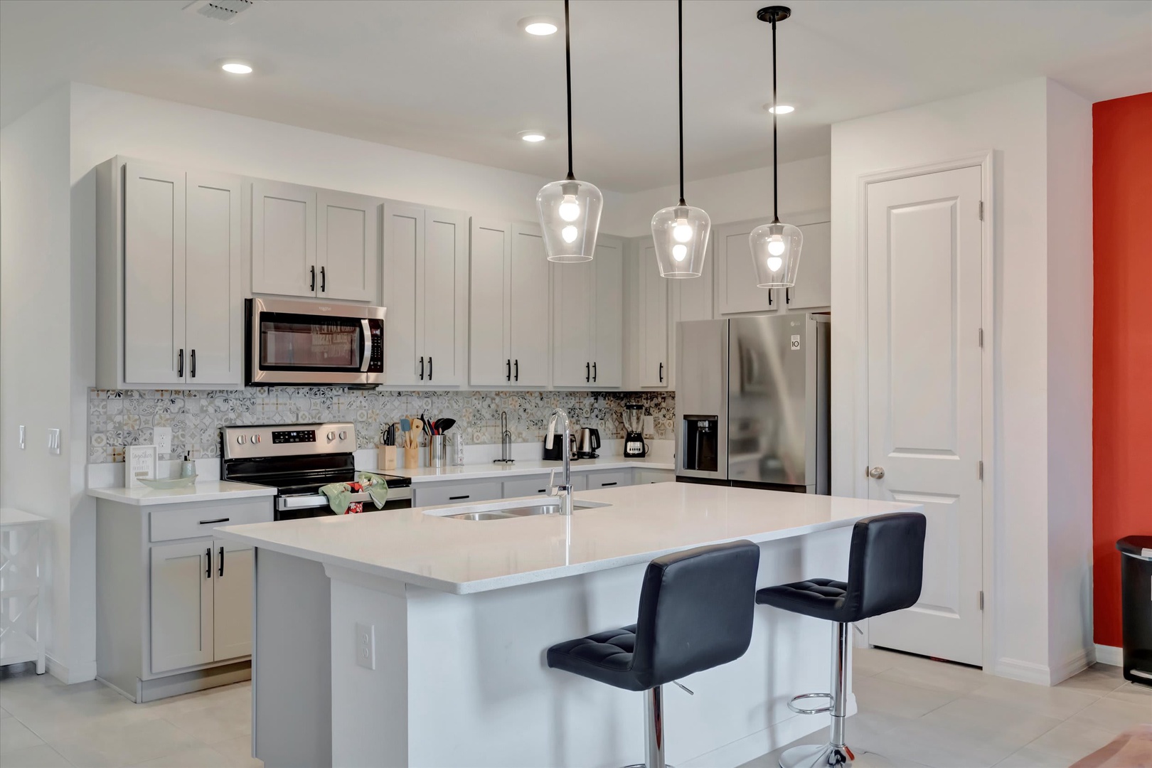 Step into your modern, fully equipped kitchen with sleek white cabinetry, stainless steel appliances, and a spacious island where you can prepare meals or enjoy morning coffee.