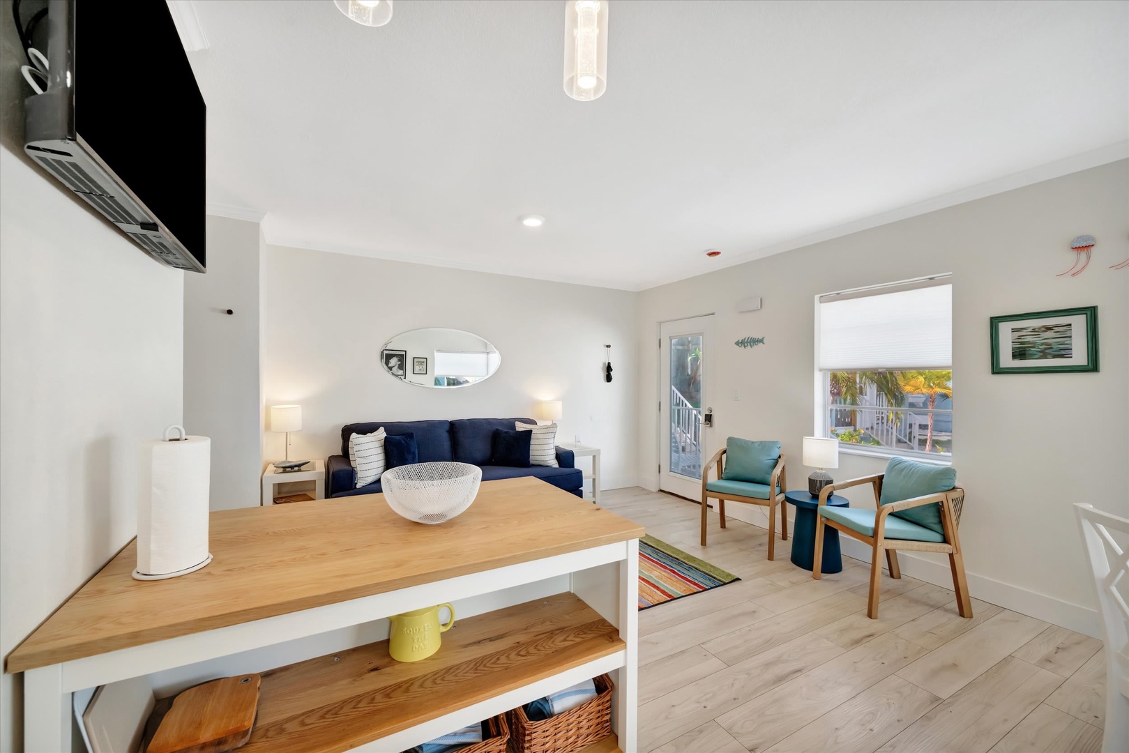 Settle into this bright, airy living space where coastal charm meets modern comfort. Sink into the navy sofa, enjoy morning coffee at the wood-topped island, and let natural light pour through the open layout, inviting you to relax and feel at home.
