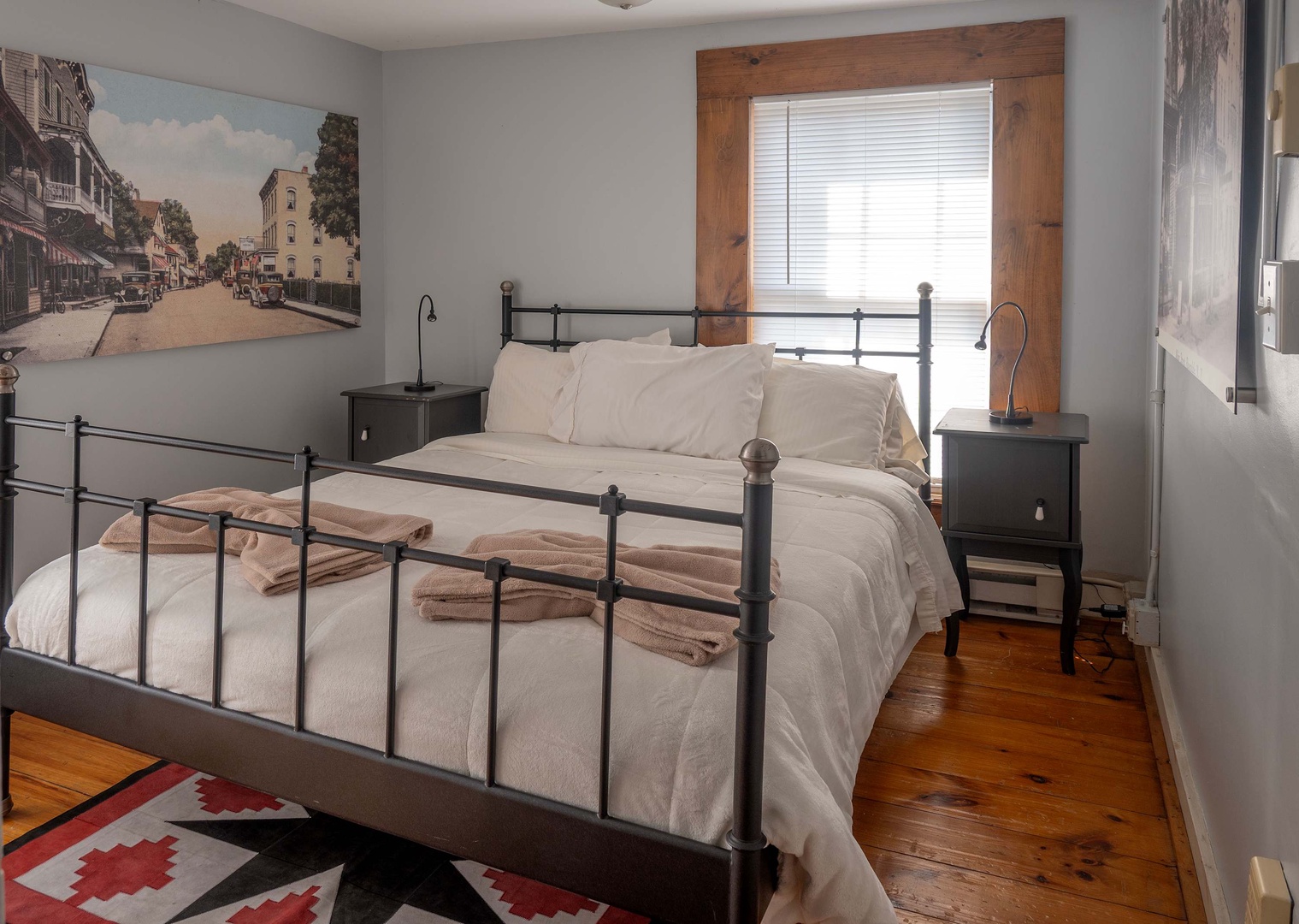 Sink into crisp white linens and feel the gentle warmth of sunlight streaming through the window. Your restful retreat awaits with soft towels and charming hardwood floors.