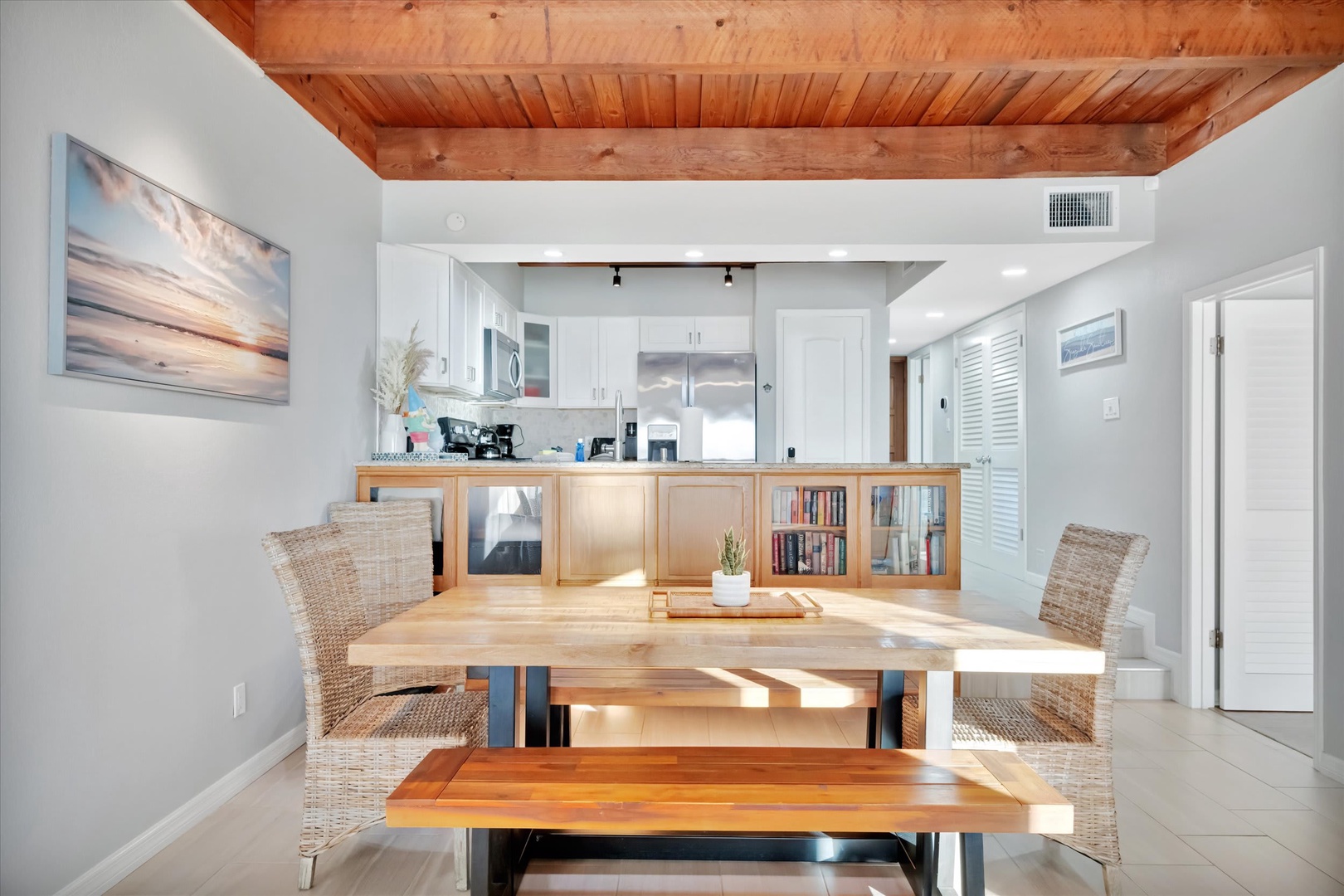 Gather around the warm wood dining table beneath soaring wood-planked ceilings that bring natural charm into your space. The open layout flows seamlessly into your fully equipped kitchen, making meal prep and togetherness effortless.