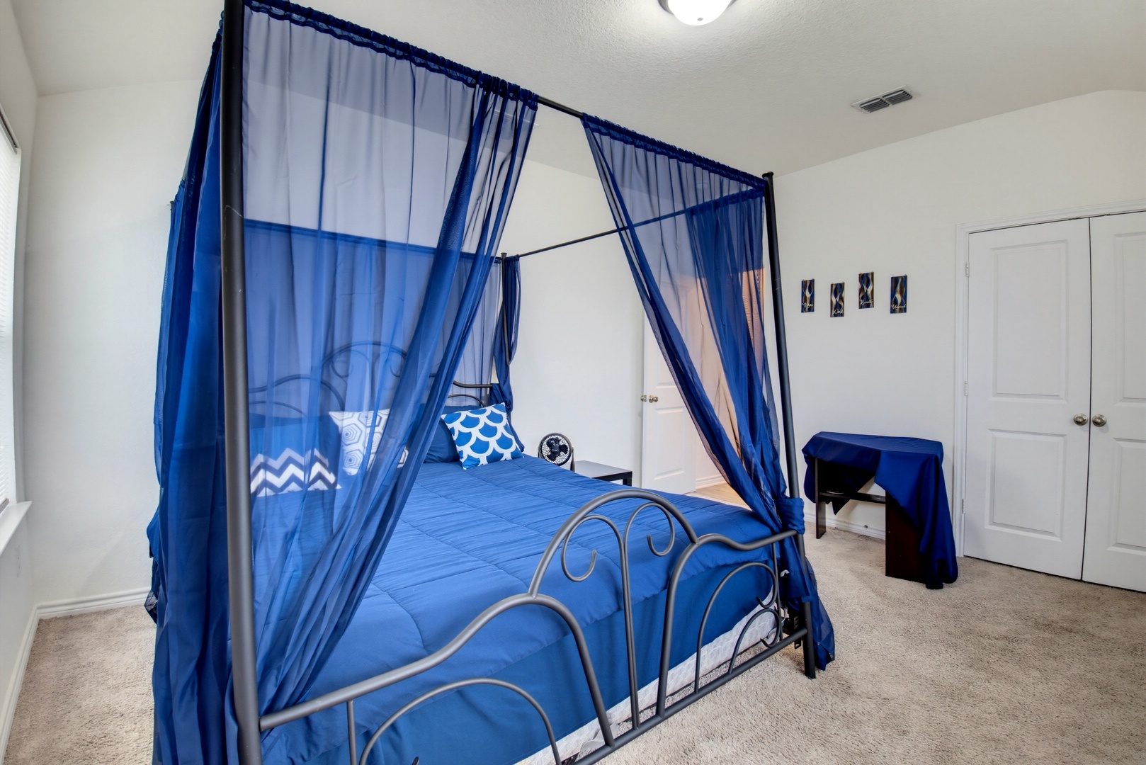 Your private sanctuary awaits with an elegant canopy bed draped in flowing sapphire curtains, creating a dreamy escape where you can drift into peaceful slumber.