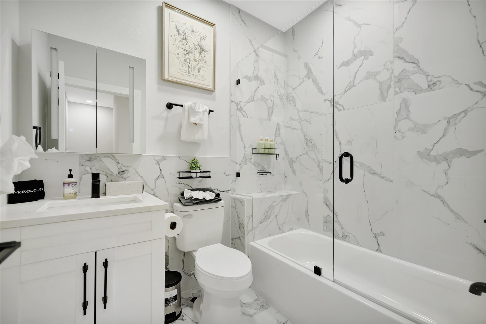 Your beautifully appointed bathroom features elegant marble-look tile, a sleek glass-enclosed tub and shower, plush towels, and upscale fixtures—everything you need to unwind in style.