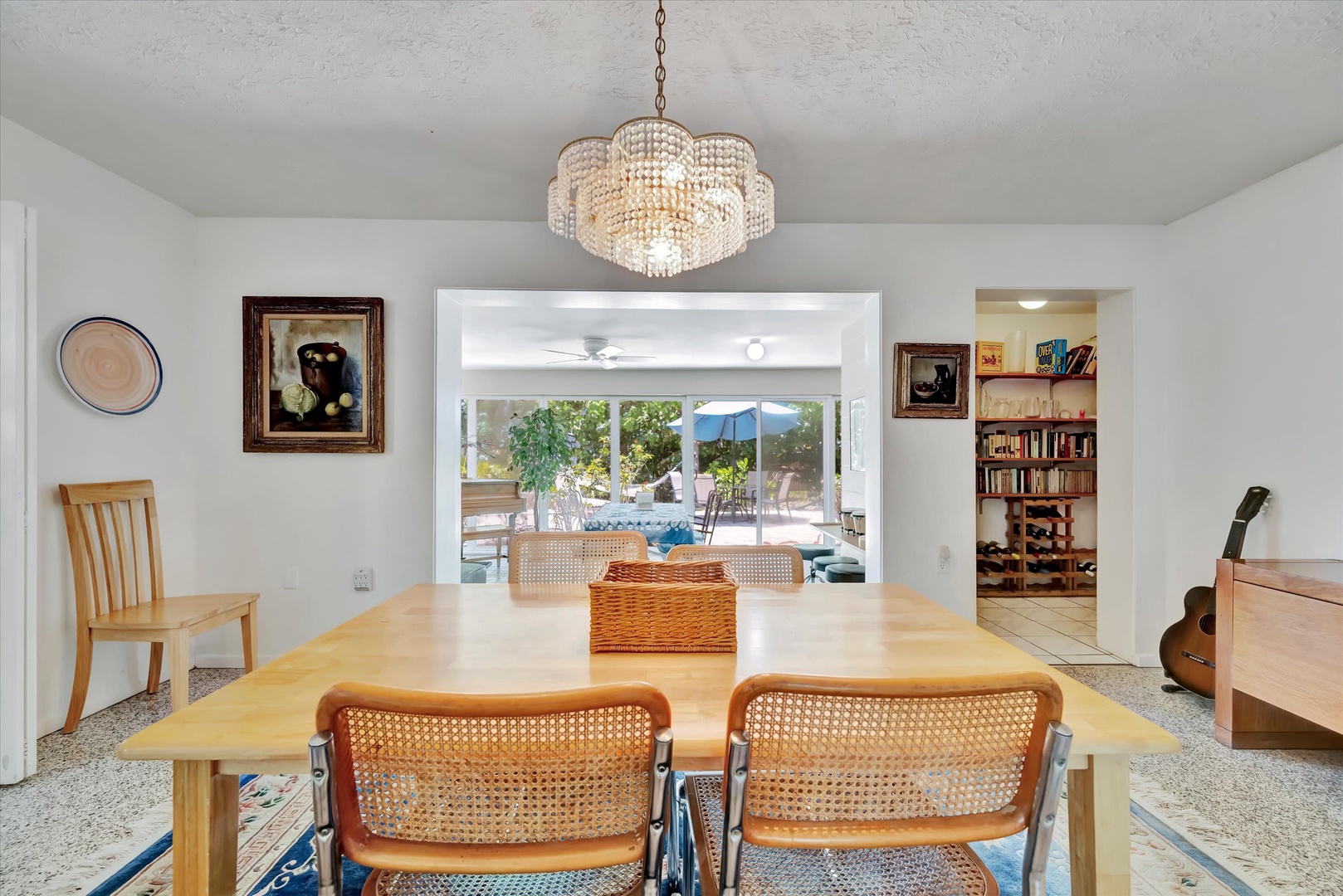 Gather around this inviting dining space where a stunning chandelier casts warm light over your meals, and glimpses of the outdoor patio beyond remind you that relaxation is just steps away.
