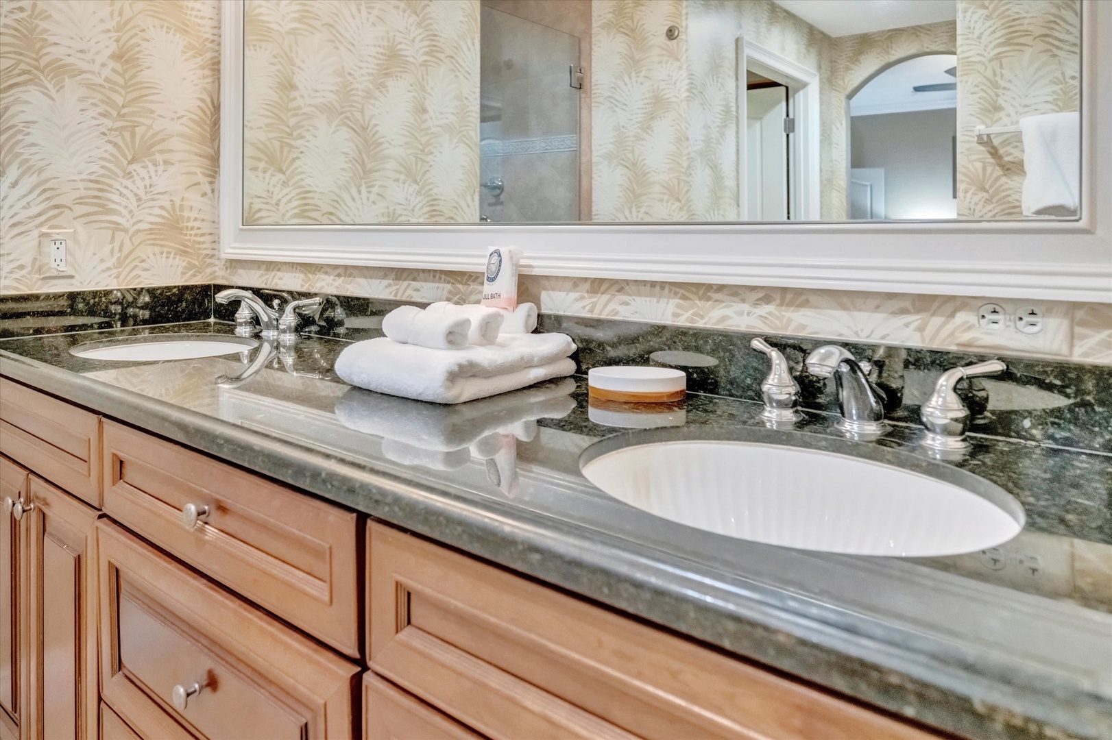 Freshen up at your spacious double vanity with elegant granite countertops, plush towels, and coastal-inspired palm décor wrapping you in relaxation.