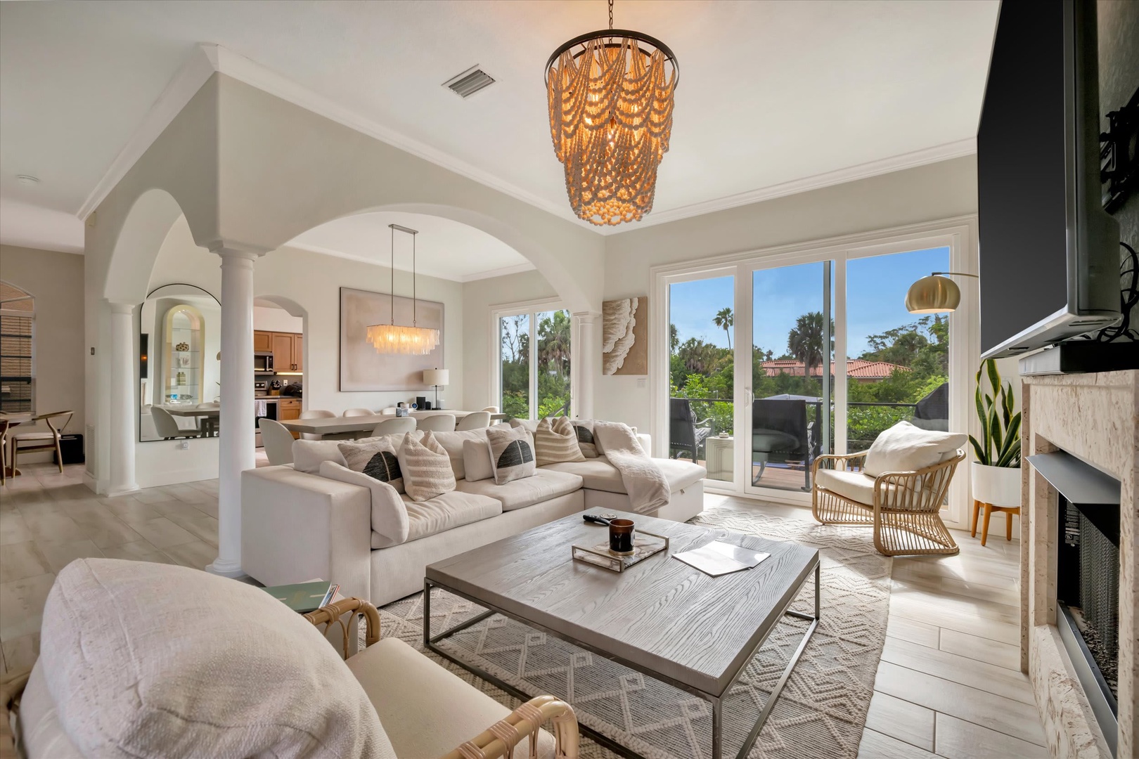 Sink into plush seating beneath a stunning chandelier while natural light frames lush garden views. This open-concept space seamlessly flows from lounge to dining, perfect for relaxation and gatherings.