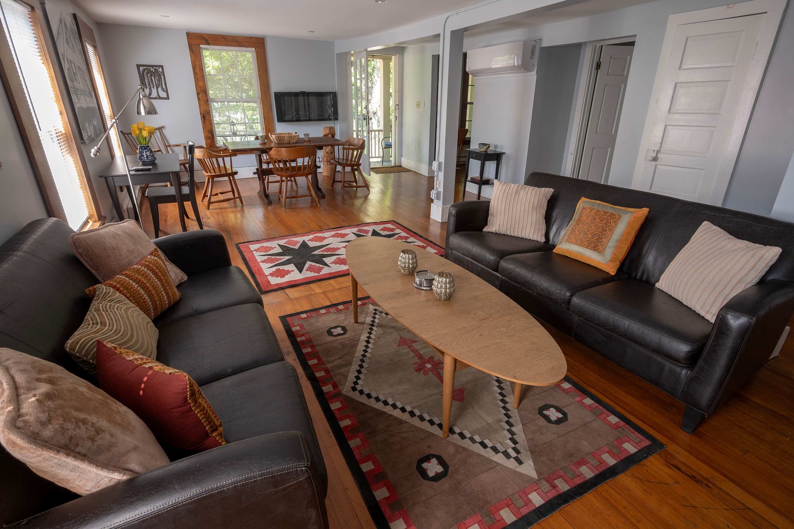 Sink into plush leather sofas in this sun-filled living space where your days flow naturally from relaxed mornings to cozy evenings together, all warmed by gleaming hardwood floors throughout.
