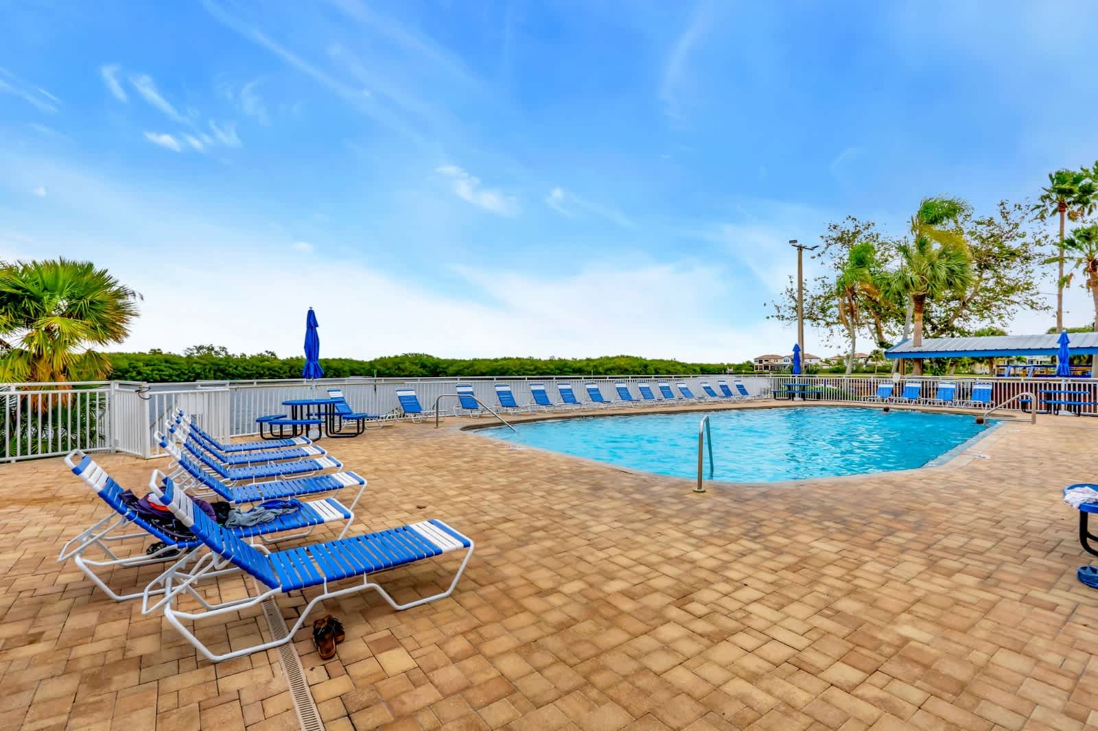 Lounge by the sparkling pool under warm sunshine, with waterside views and swaying palms completing your perfect relaxation day.