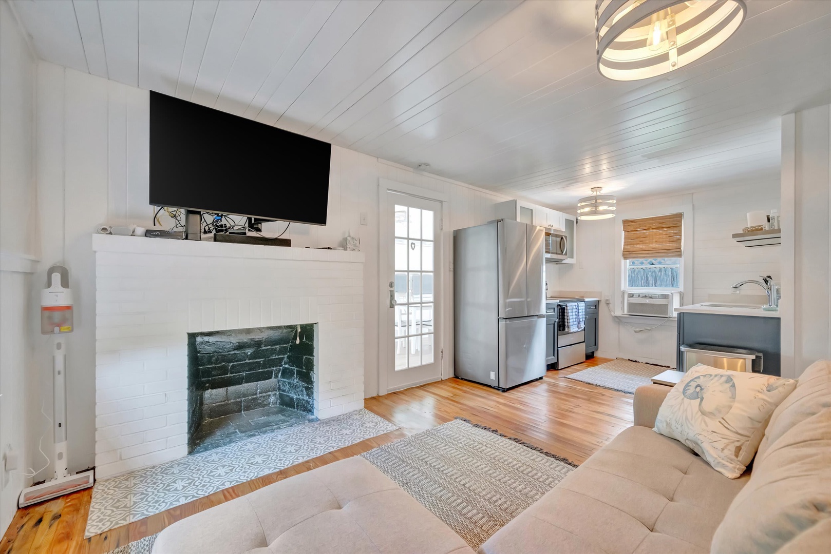 Settle into your bright coastal living space where warm hardwood floors meet coastal charm. The fireplace adds character while the open kitchen and inviting sofa create the perfect spot to unwind.