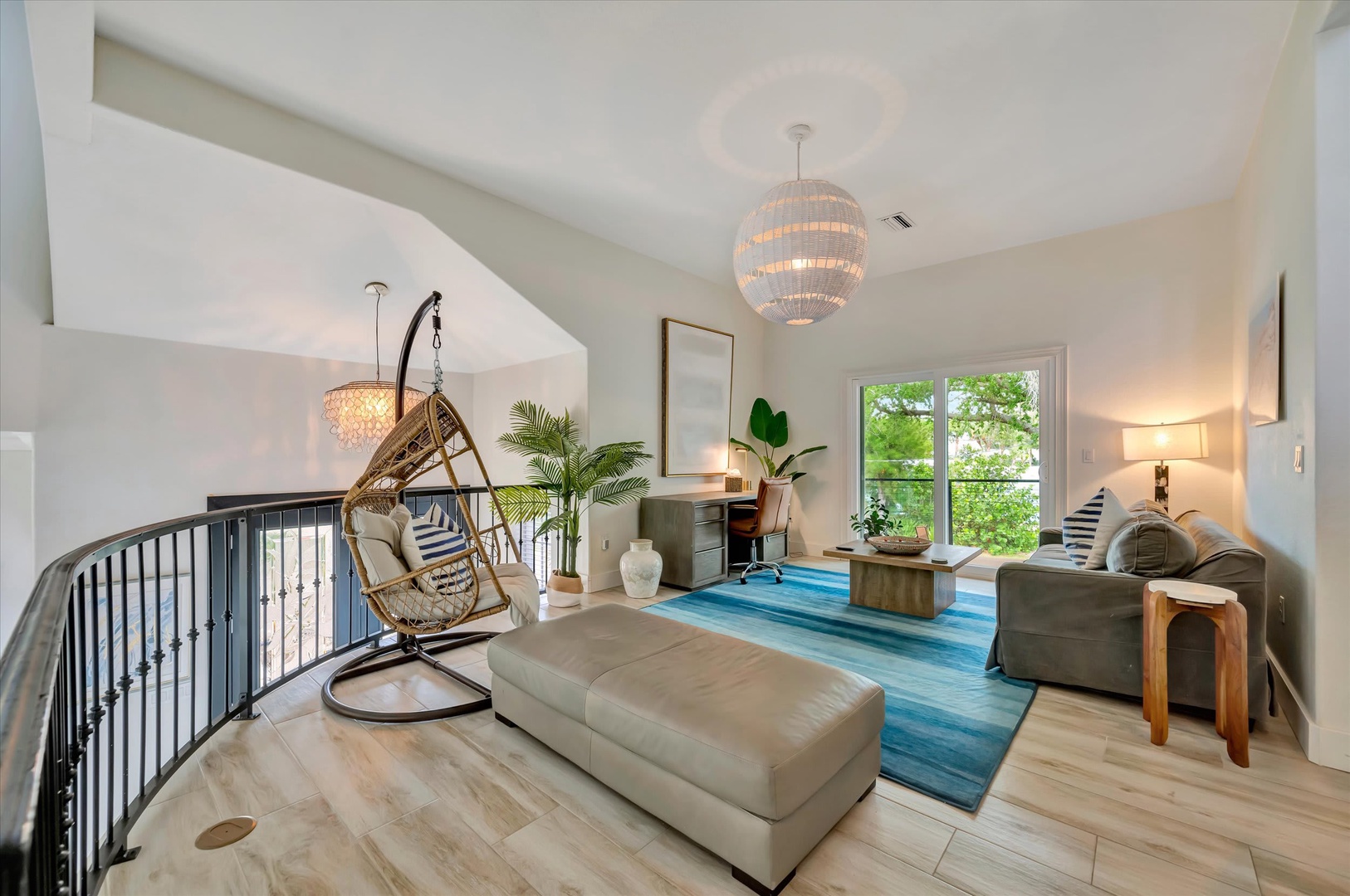 Settle into your serene loft lounge with soaring ceilings, a cozy hanging chair, and soft natural light streaming through greenery-framed windows—your perfect retreat for unwinding.