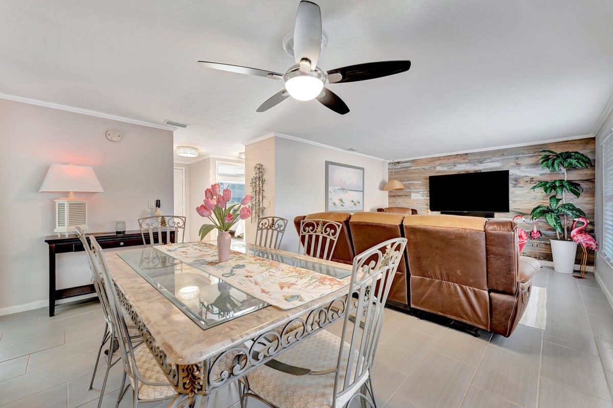 Step into your bright open-concept living space where coastal elegance meets comfort. The stylish dining table invites you to gather, while the cozy living area beckons for evening relaxation.