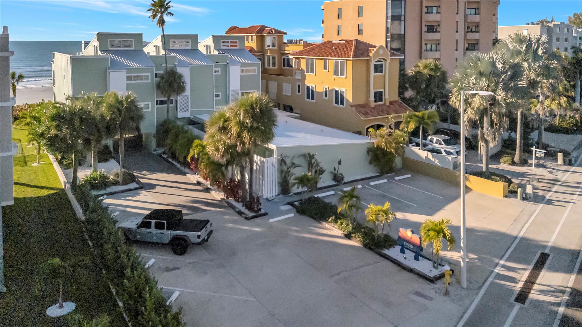 An aerial view of the property showcasing its prime beachfront location, surrounded by palm trees and neighboring coastal architecture, with easy access to the ocean.