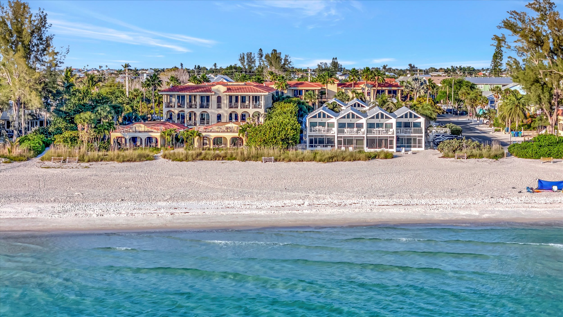 Beachfront property nestled between sandy shores and lush tropical landscaping, offering direct access to turquoise waters and coastal charm.