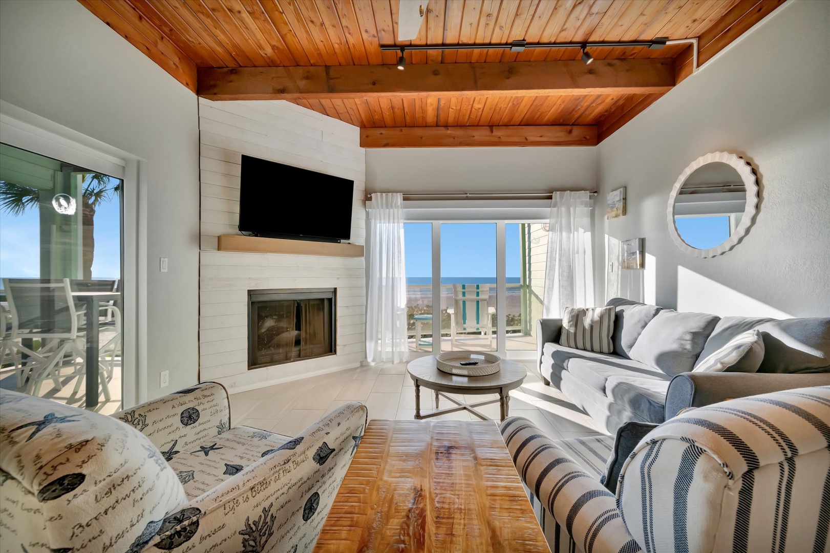 Unwind in your bright, airy living room where warm wood tones meet coastal elegance. Curl up by the fireplace while ocean views frame your perfect beach escape.