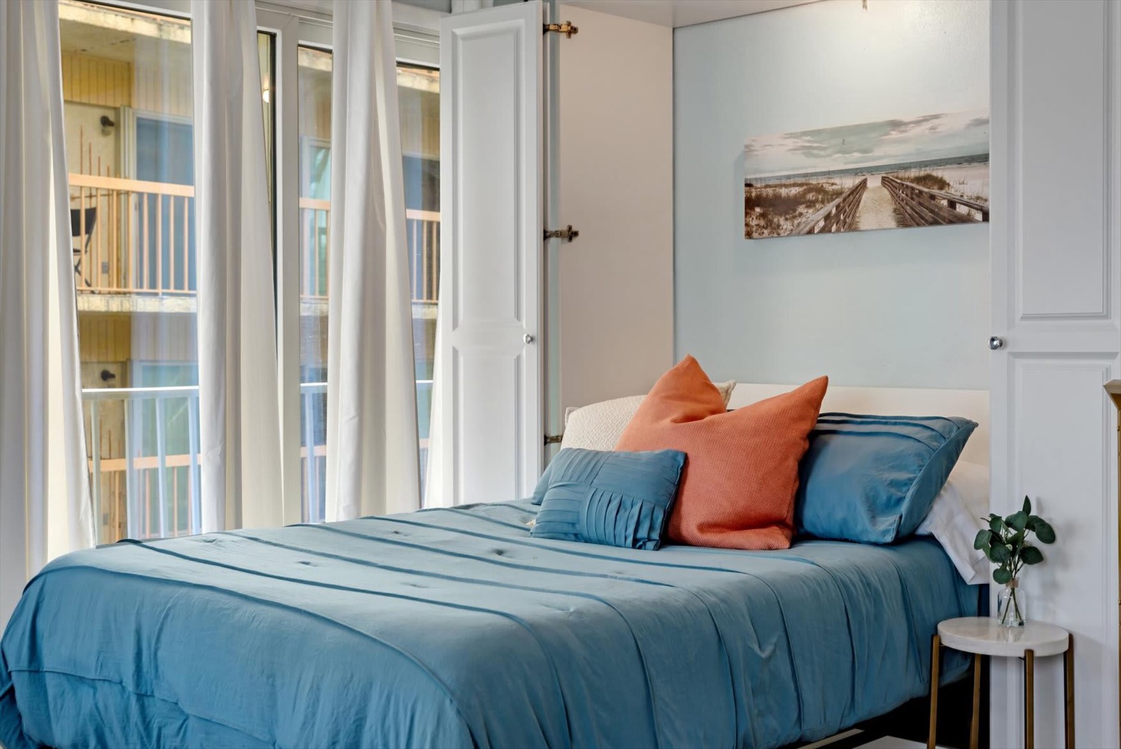 Sink into comfort in your serene bedroom retreat. Soft linens and calming coastal colors invite restful nights, while glass doors open to your private balcony for morning light and fresh air.