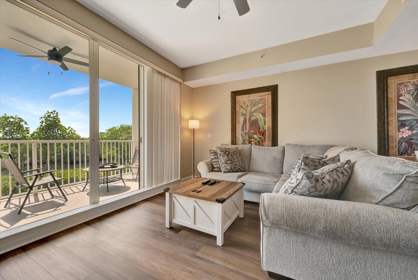 Unwind on your soft sectional sofa and enjoy the warm natural light streaming through sliding glass doors that open to your private balcony, where lush treetops frame a peaceful retreat.