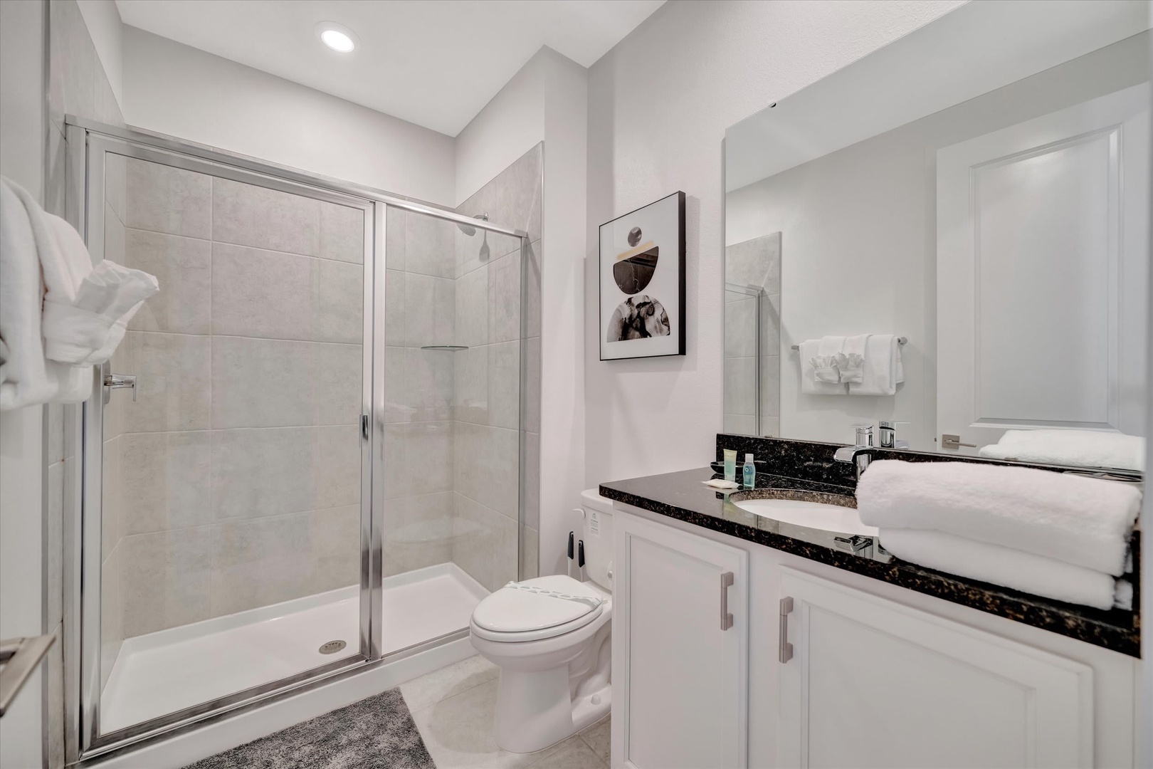 Step into this bright, modern bathroom where crisp lines and neutral tones create a spa-like retreat. A spacious walk-in shower and polished vanity with fresh towels await your arrival.