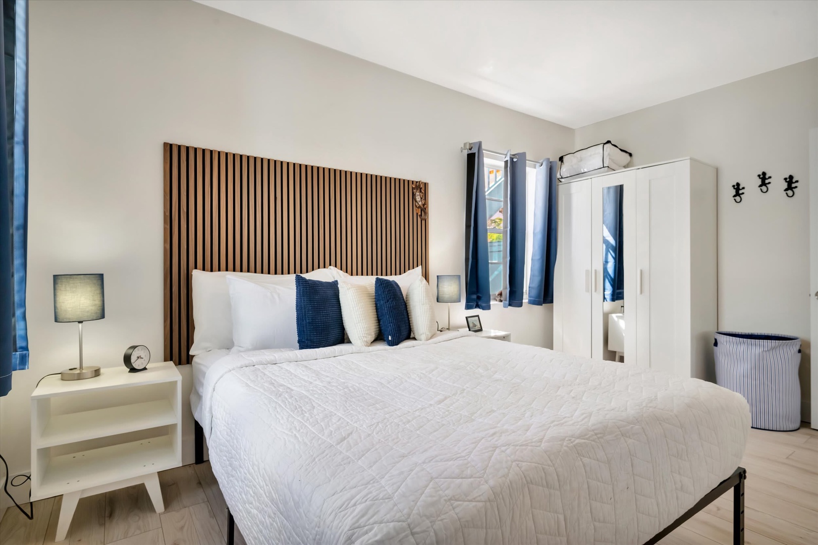 Sink into crisp white linens beneath the striking wooden headboard, your personal retreat designed for deep, restful sleep and peaceful mornings.