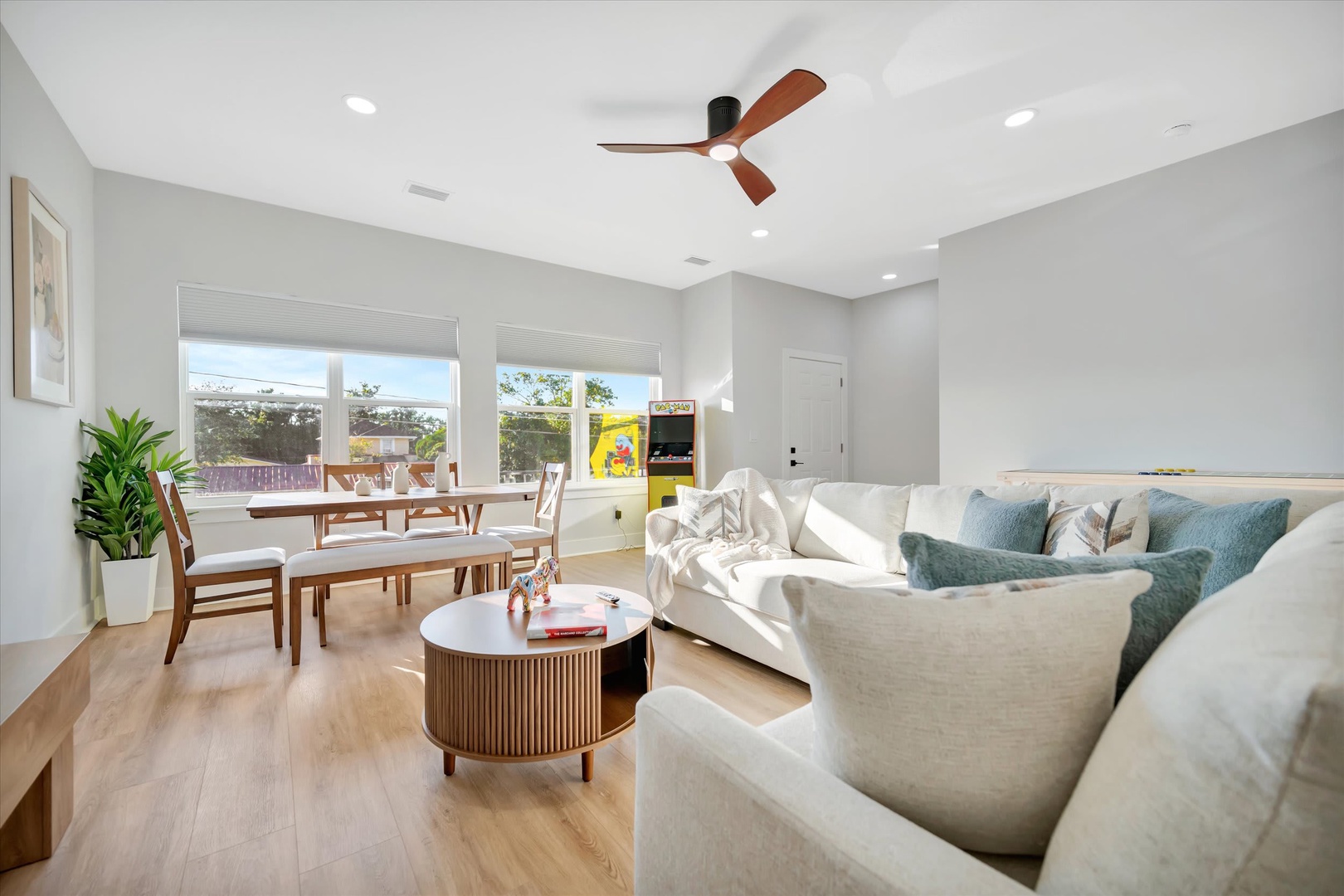 Sink into plush seating in this airy, light-filled living space. Natural wood tones, cheerful greenery, and windows framing outdoor views create a serene, welcoming vibe for your stay.