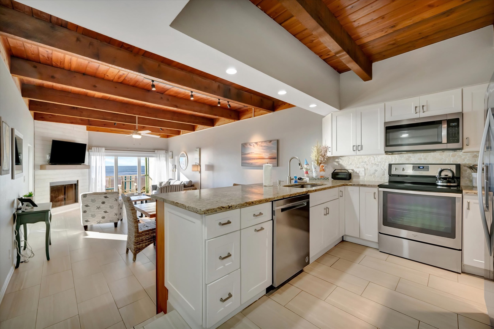 Cook up your favorite meals in this bright, fully equipped kitchen while soaking in the stunning ocean view just beyond your living space. The warm wood beam ceiling and open layout make it easy to enjoy coastal living at its best.