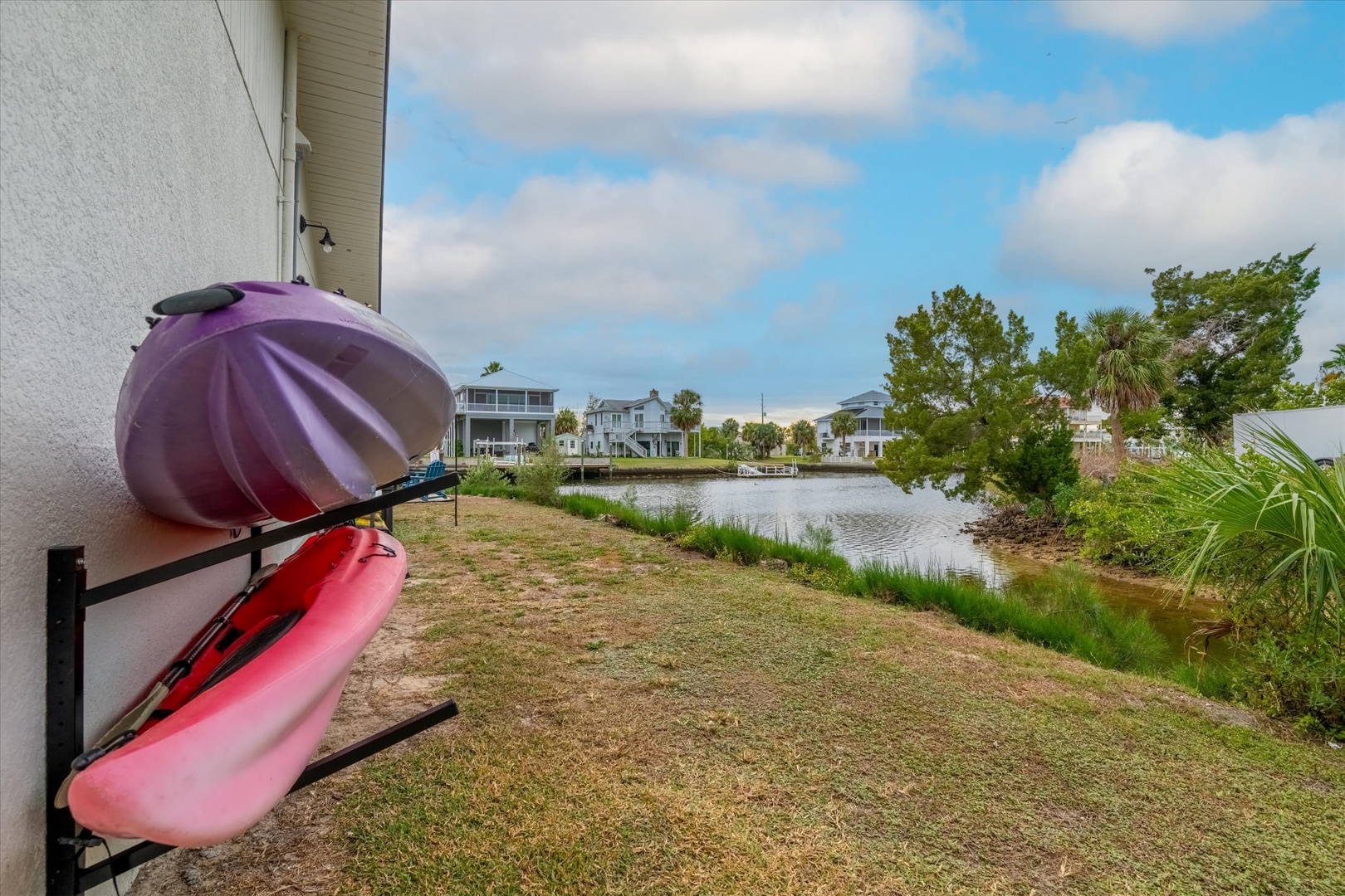 A kayak awaits your next adventure along the peaceful waterway, where neighbors share serene lake views beneath blue skies.