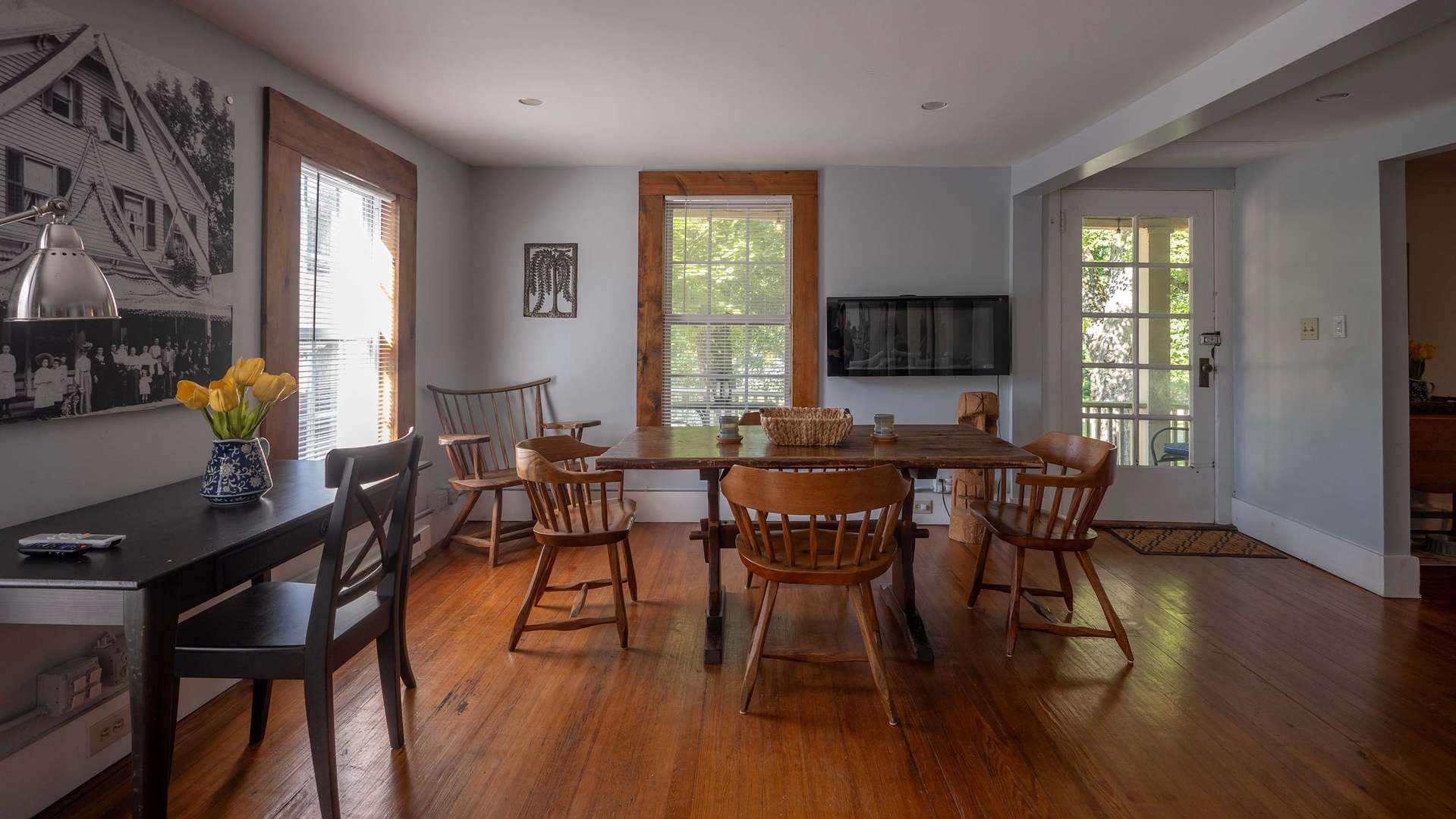 Gather around the farmhouse table for meals and laughter in this charming dining space with warm wood floors, natural light streaming through the windows, and a cozy blend of rustic and modern touches.