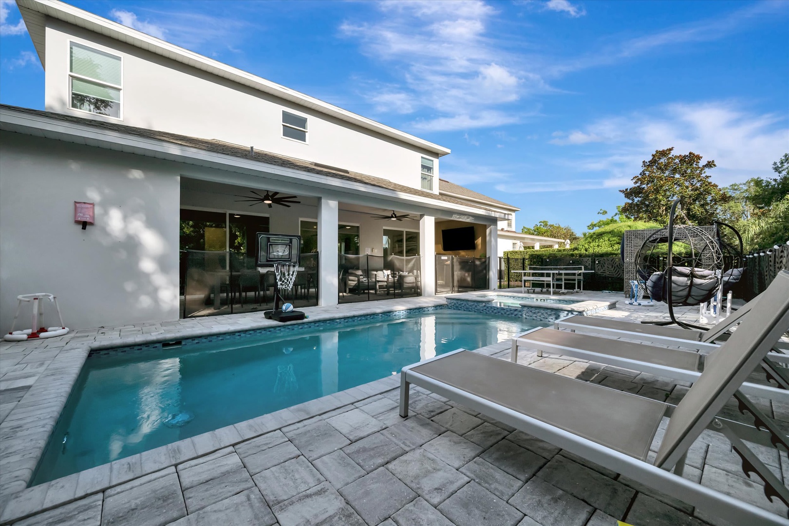 Step outside to your private backyard paradise—a sparkling pool framed by modern loungers and lush Florida greenery, perfect for relaxing under the sun or unwinding in the shade.