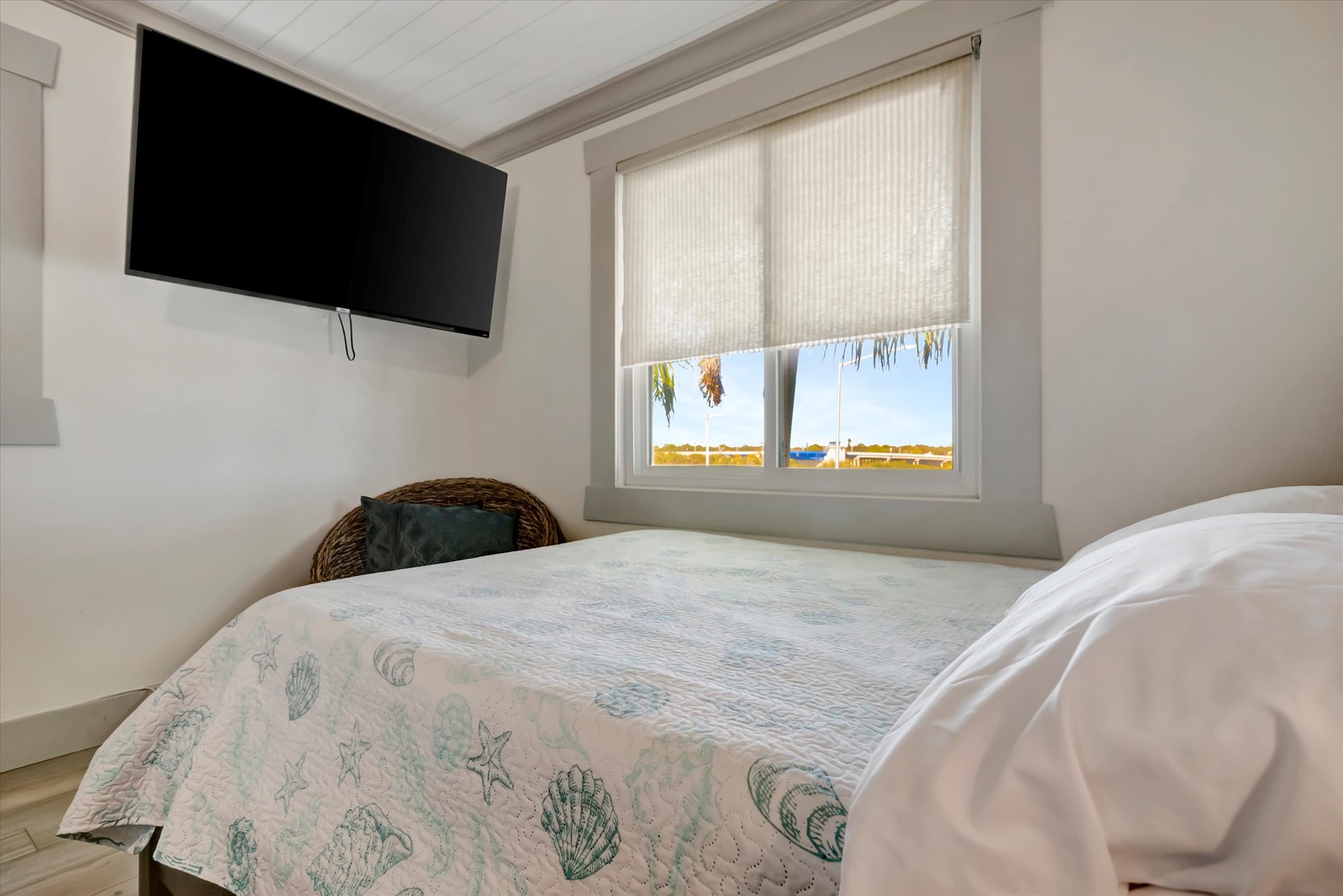 Wake up in this bright coastal bedroom where soft linens and serene views greet your mornings. Natural light filters through shades, while your private TV and peaceful harbor scene await just beyond the glass.