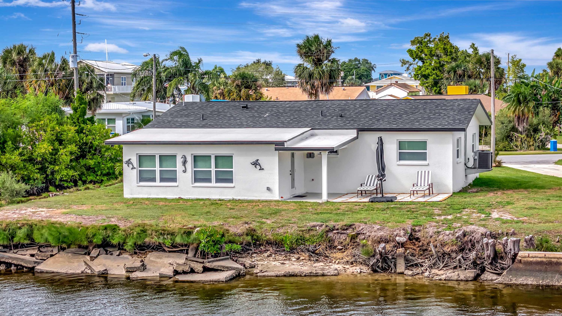 A charming waterfront retreat with direct access to calm canal waters. The property sits in a quiet residential neighborhood surrounded by palm trees and tropical greenery.