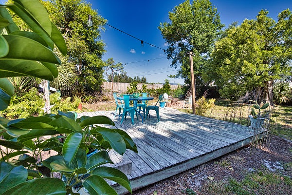 A sunny deck surrounded by lush greenery offers the perfect spot for your morning coffee or evening glass of wine under string lights.