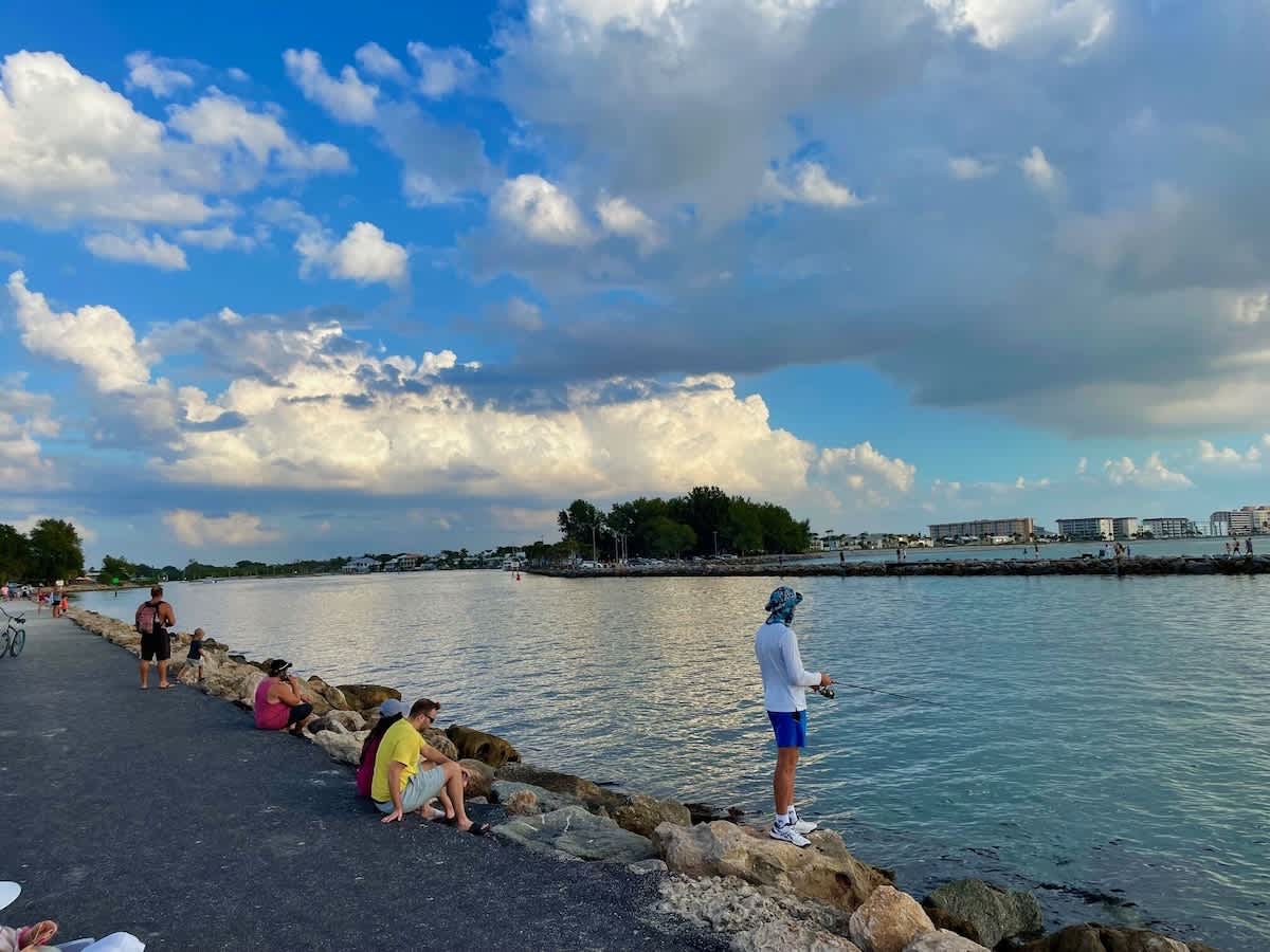 A picturesque waterfront area near the property, where guests gather along the shore under dramatic cloud formations and enjoy waterside activities.