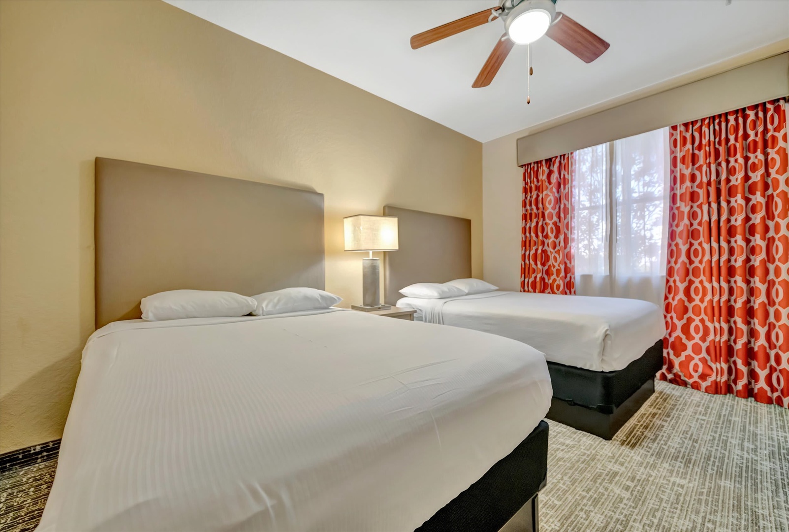 Unwind in your spacious bedroom with fresh linens and two plush beds, perfect for restful nights. Bright natural light and a gentle ceiling fan keep the room airy and comfortable.