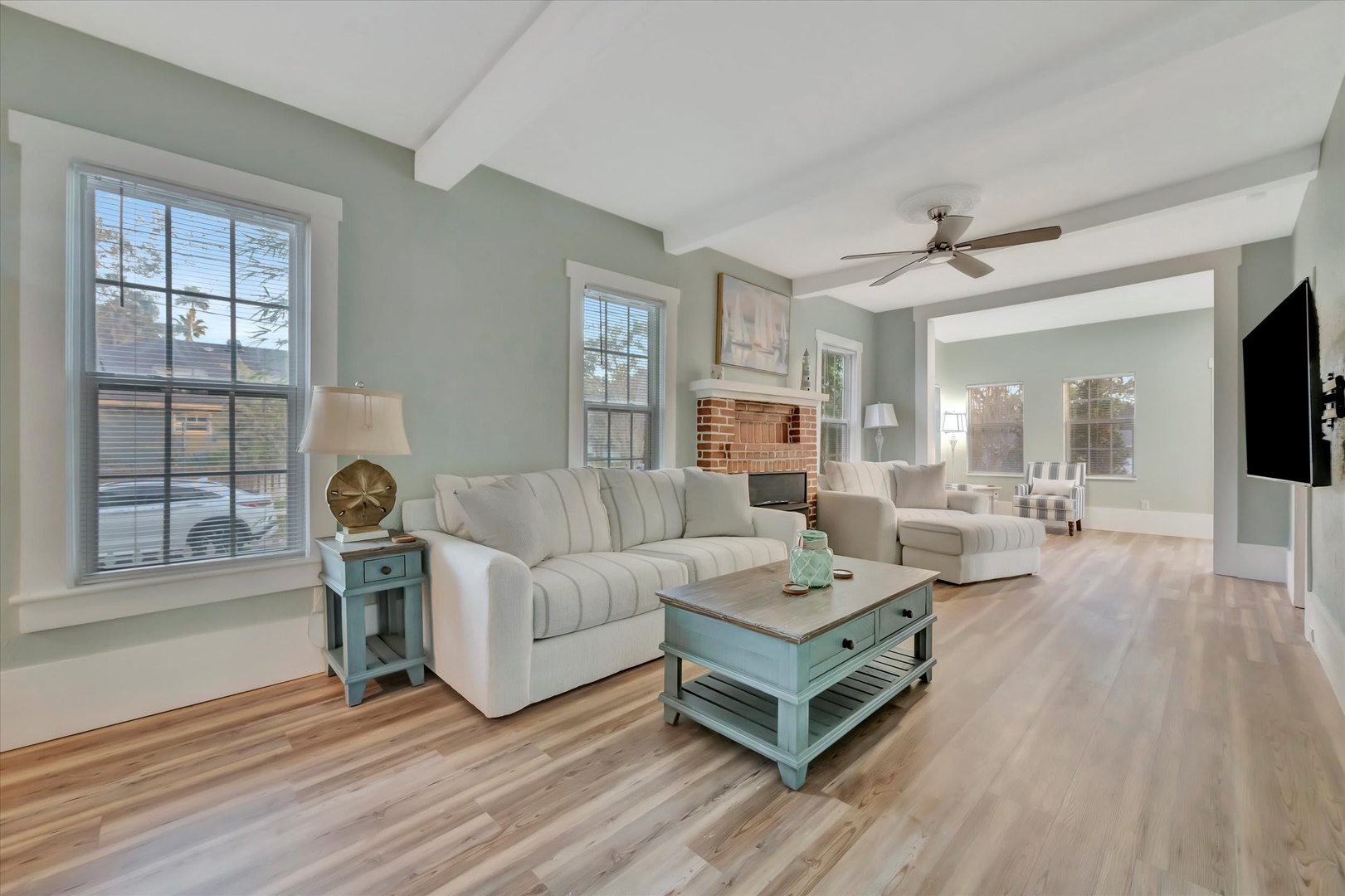 Sink into plush seating as natural light pours through tall windows, warming the gleaming hardwood floors beneath your feet. The open layout invites you to unwind in calming coastal tones.