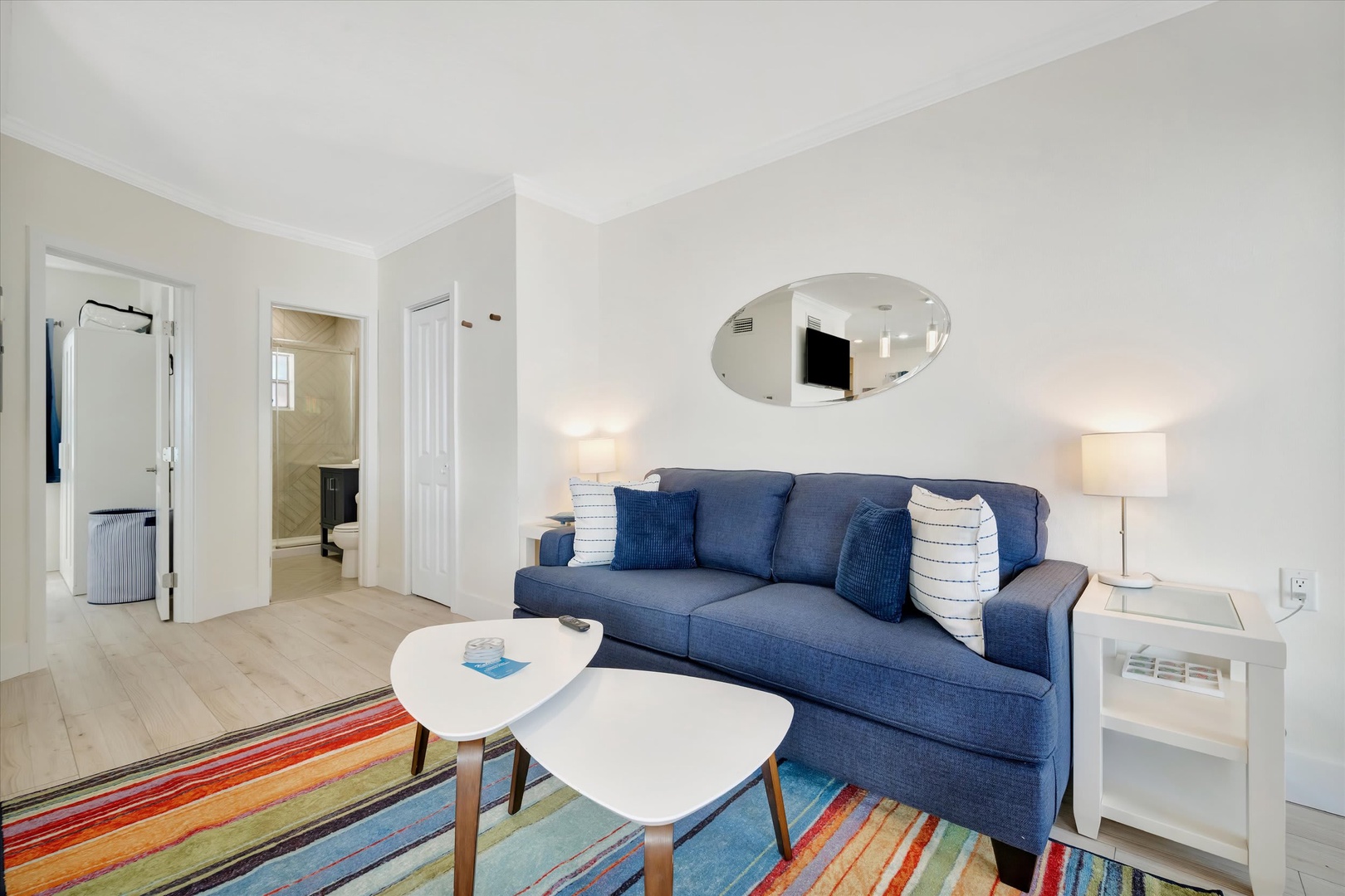 Settle into this bright, inviting living space with a cozy blue sofa and colorful striped rug. You'll love the airy, open design that flows into the adjoining bedroom—perfect for relaxing after a day of adventure.