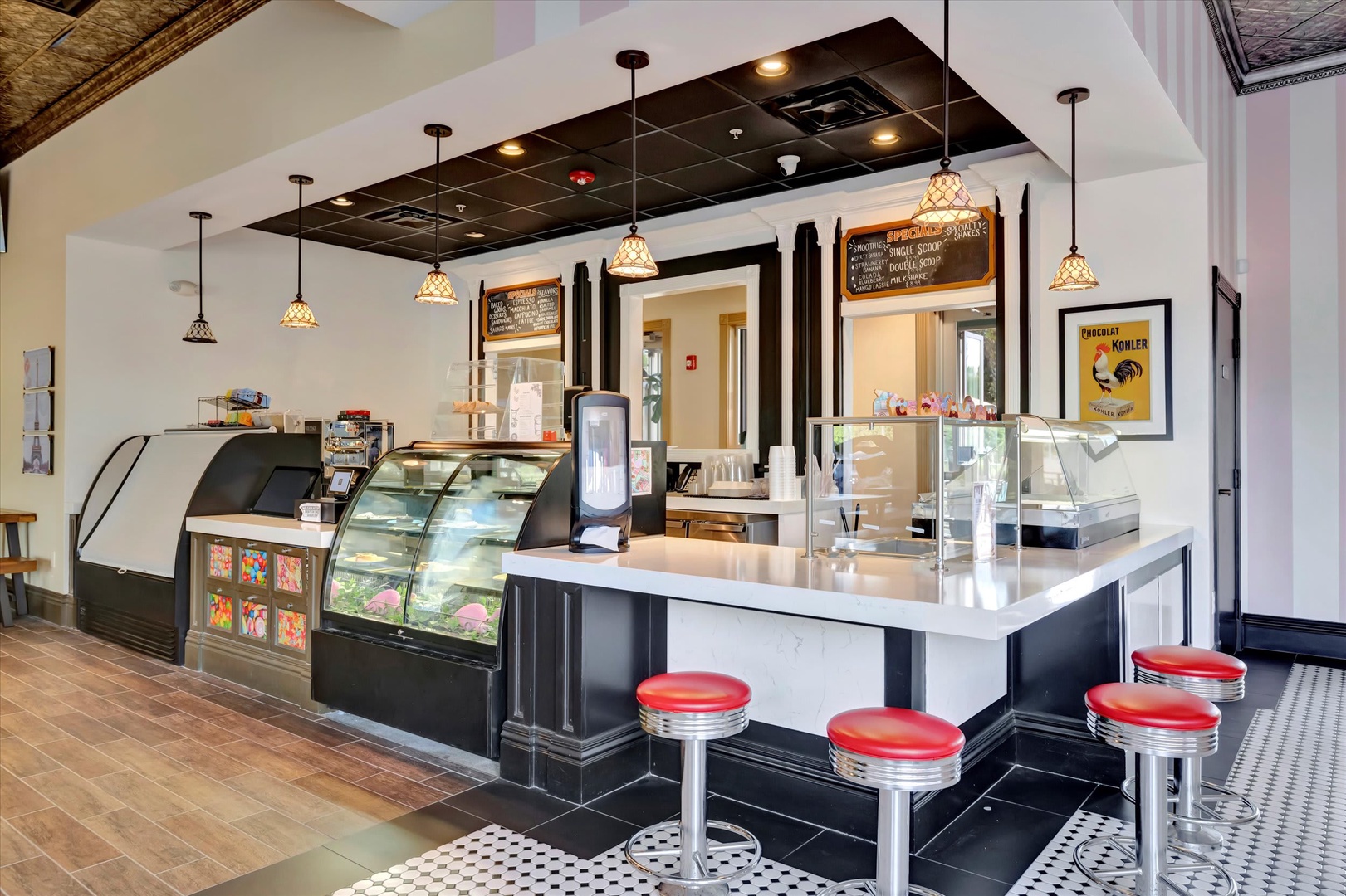 A charming retro-style ice cream shop or café awaits nearby, featuring vintage pendant lights, classic red vinyl stools, and cheerful display cases filled with sweet treats.