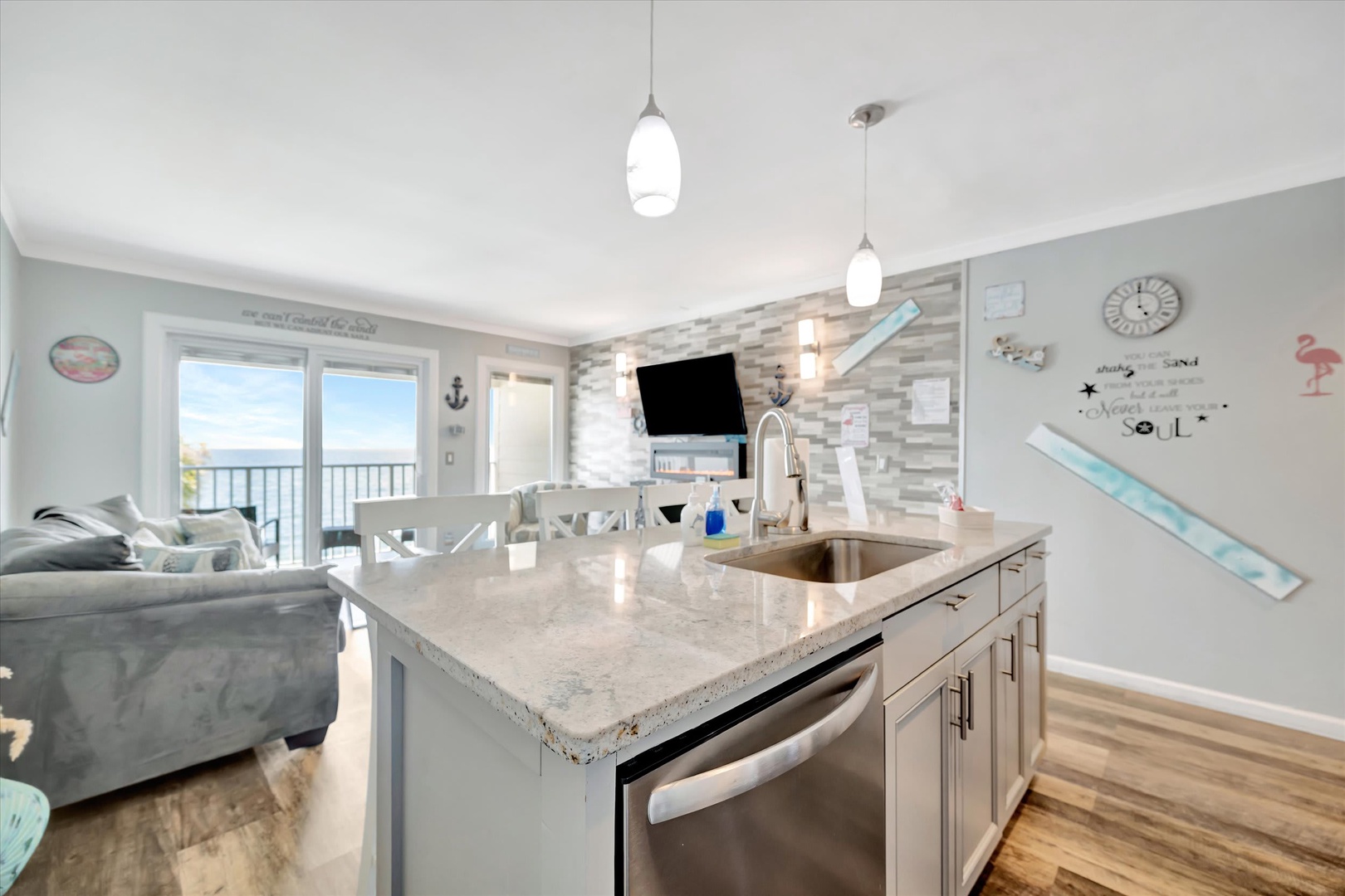 Your coastal retreat blends style and comfort with an open kitchen island, modern appliances, and sweeping ocean views visible through bright sliding glass doors.