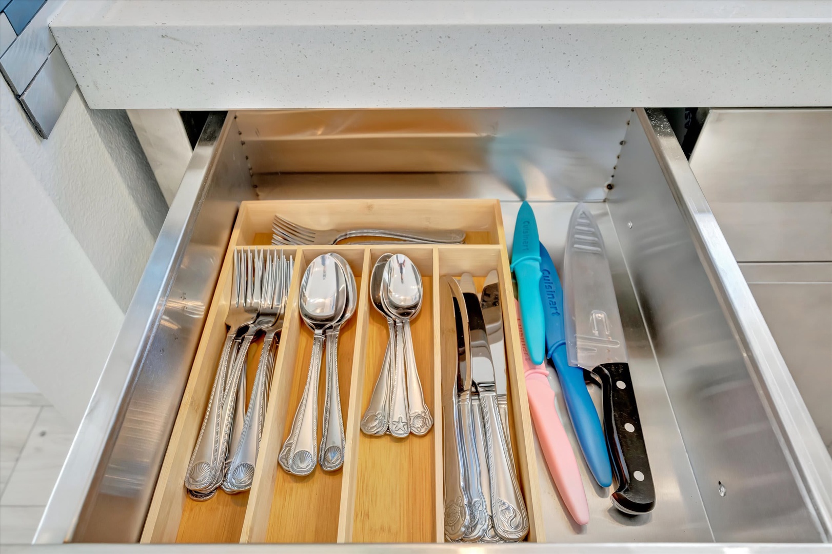 A well-organized drawer with gleaming flatware and sharp knives awaits your culinary adventures in this thoughtfully equipped kitchen.