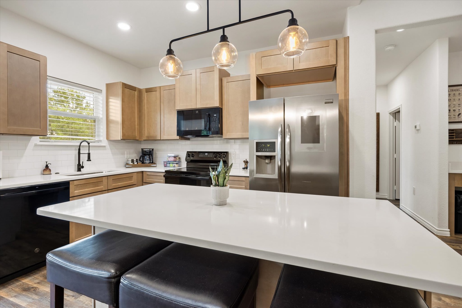 Step into your bright modern kitchen with warm wood cabinetry, sleek white quartz counters, and a spacious island perfect for morning coffee or meal prep. Everything you need is here—ready for you to settle in and feel at home.