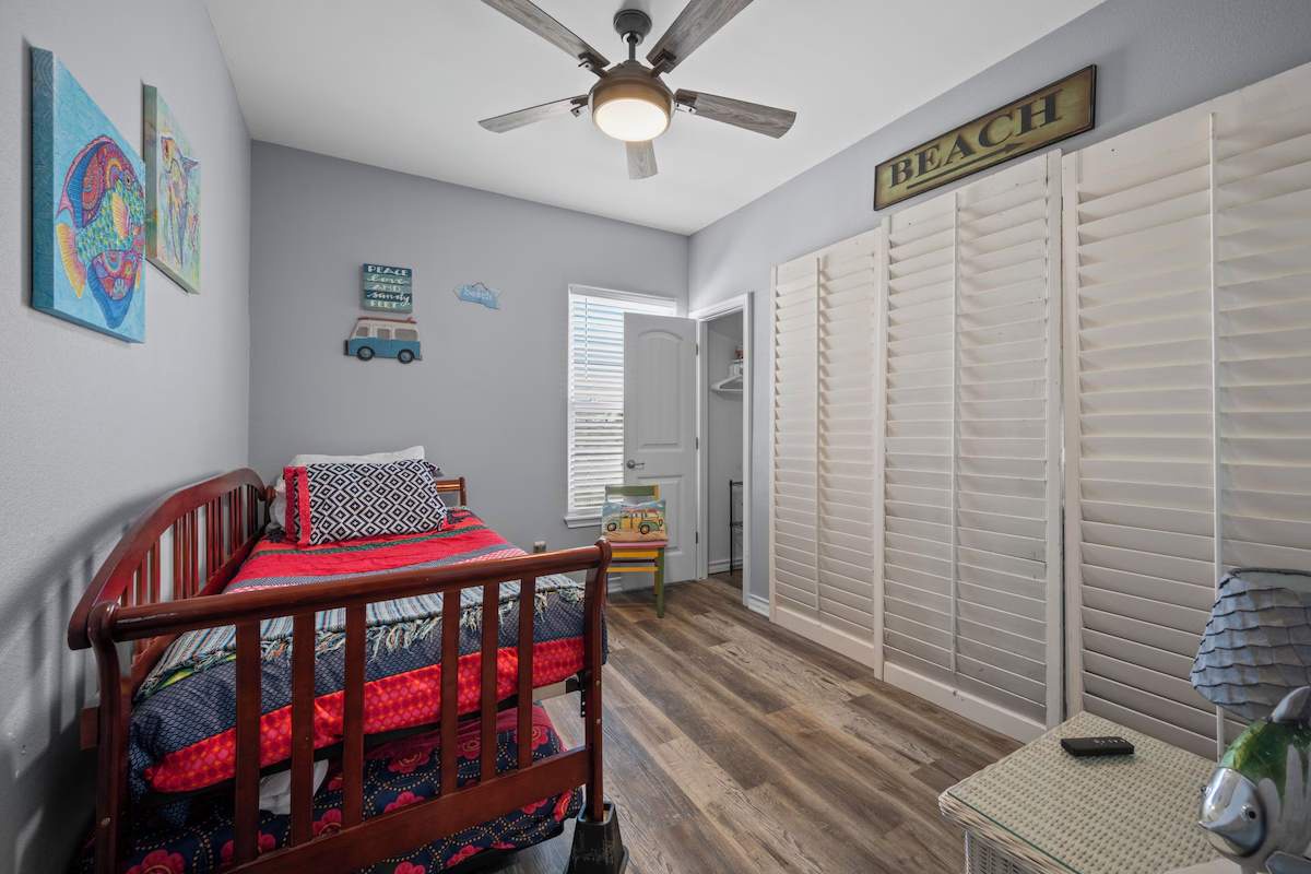 Your cozy beach-themed bedroom awaits with charming decor, a ceiling fan for comfort, and plenty of storage space behind louvered doors.